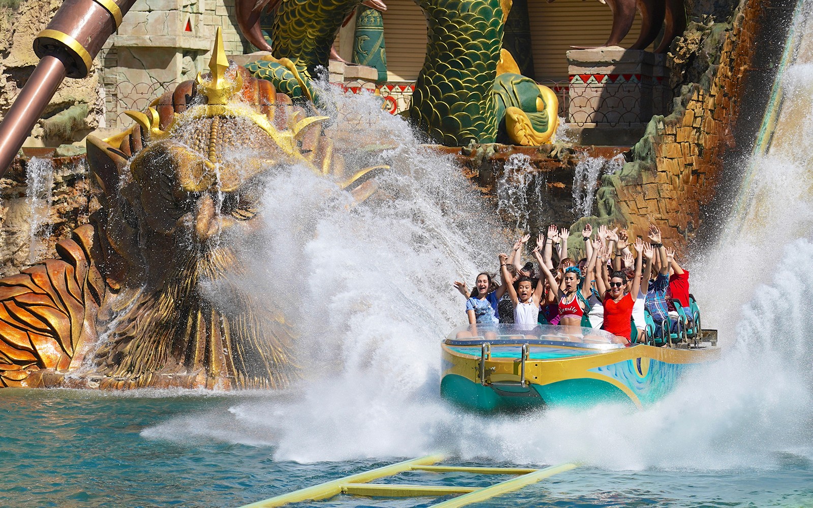 Návštěvníci si užívají vzrušující vodní jízdu v Gardaland Parku s pozadím dračí sochy.