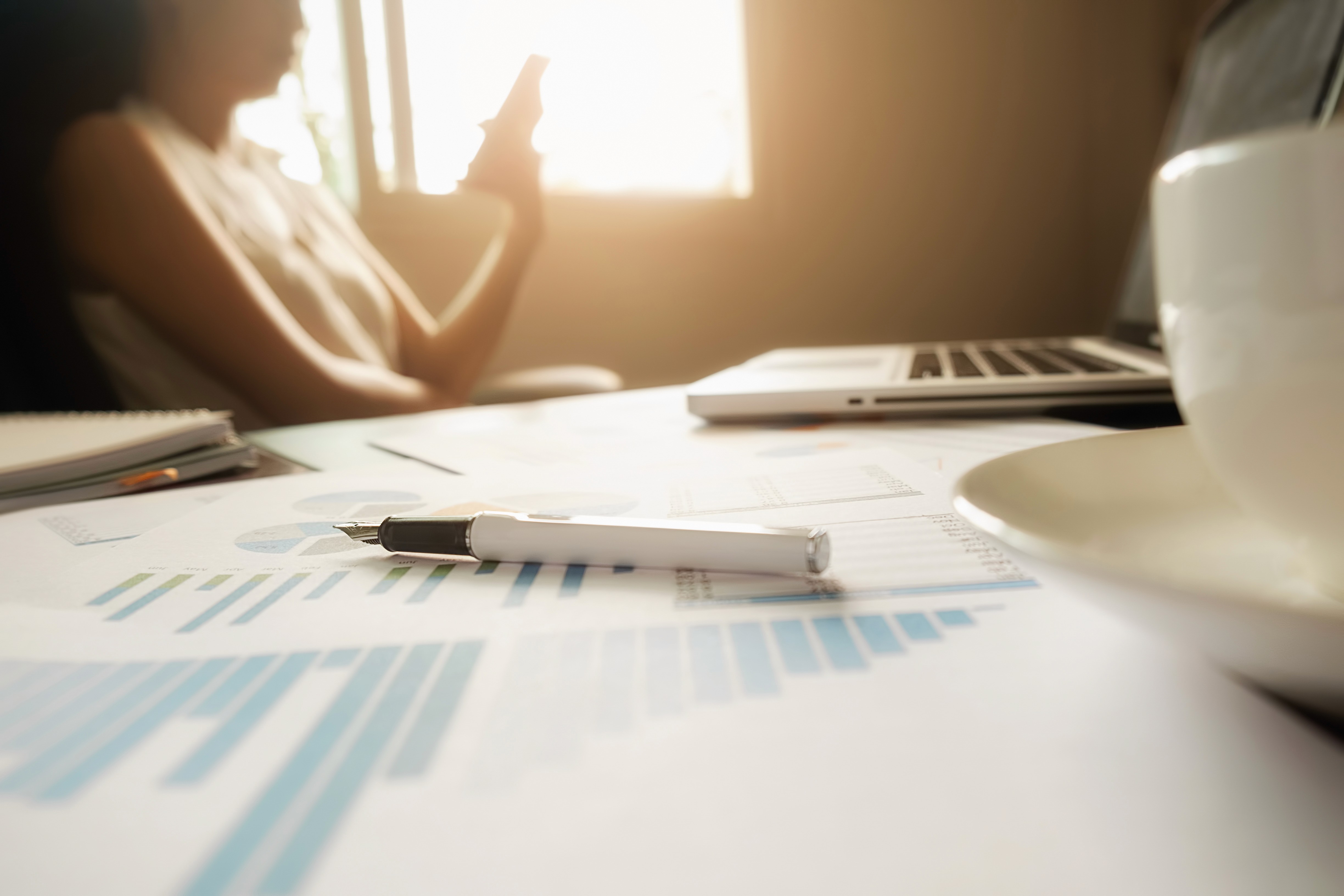 Mesa de escritório com computador exibindo gráficos e indicadores de gestão hospitalar