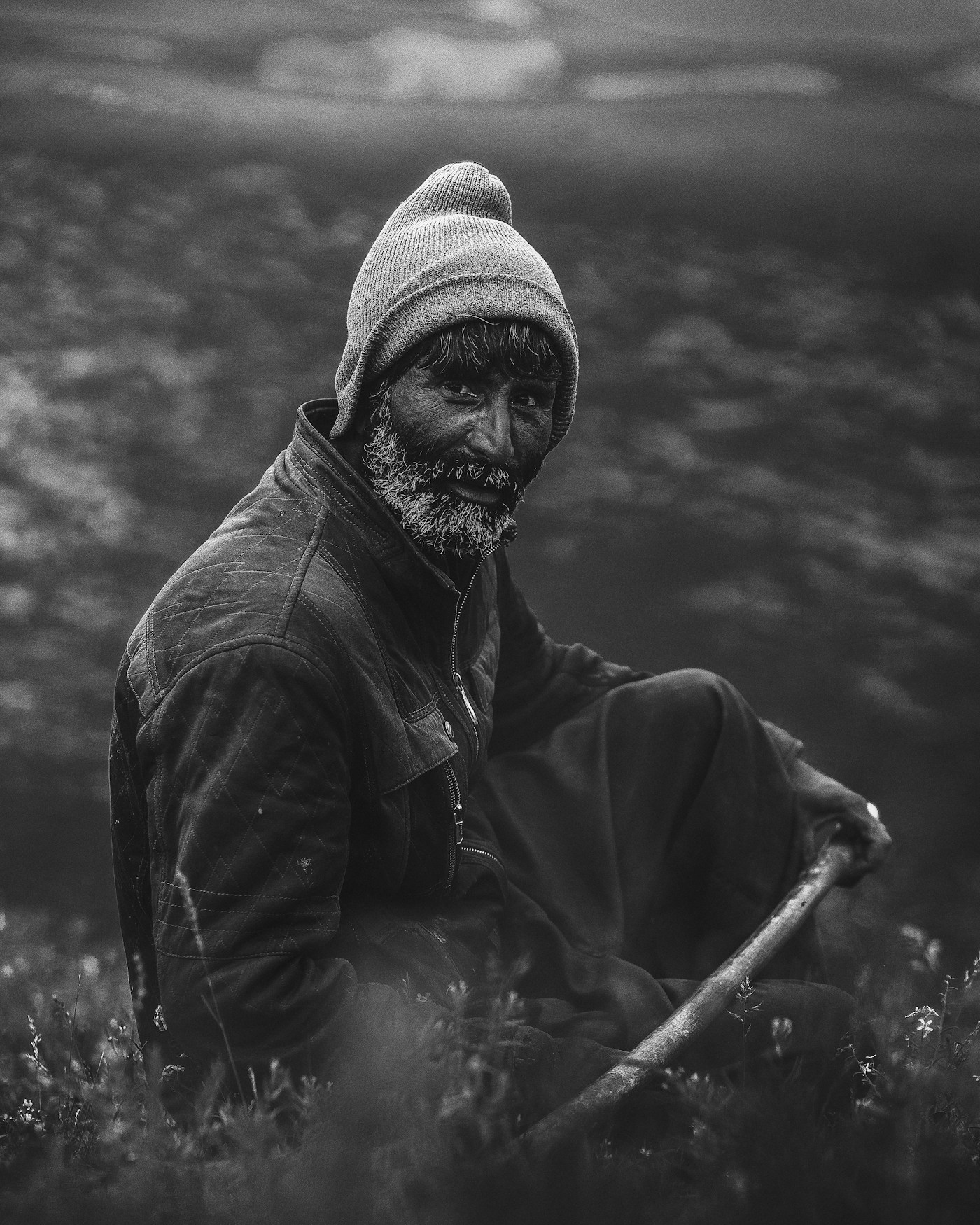 A fisherman in a knitted hat resting on the shore
