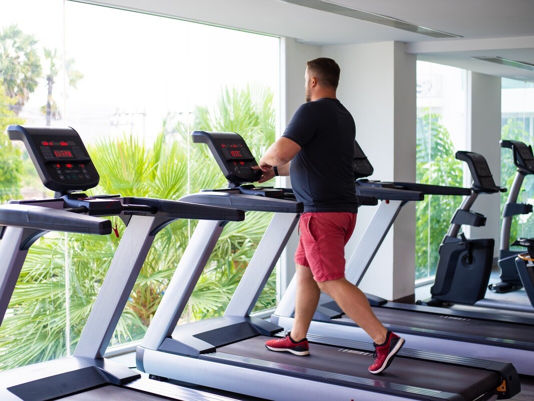 plus-sized man doing a brisk 60-minute walk showing the best way to lose weight on a treadmill