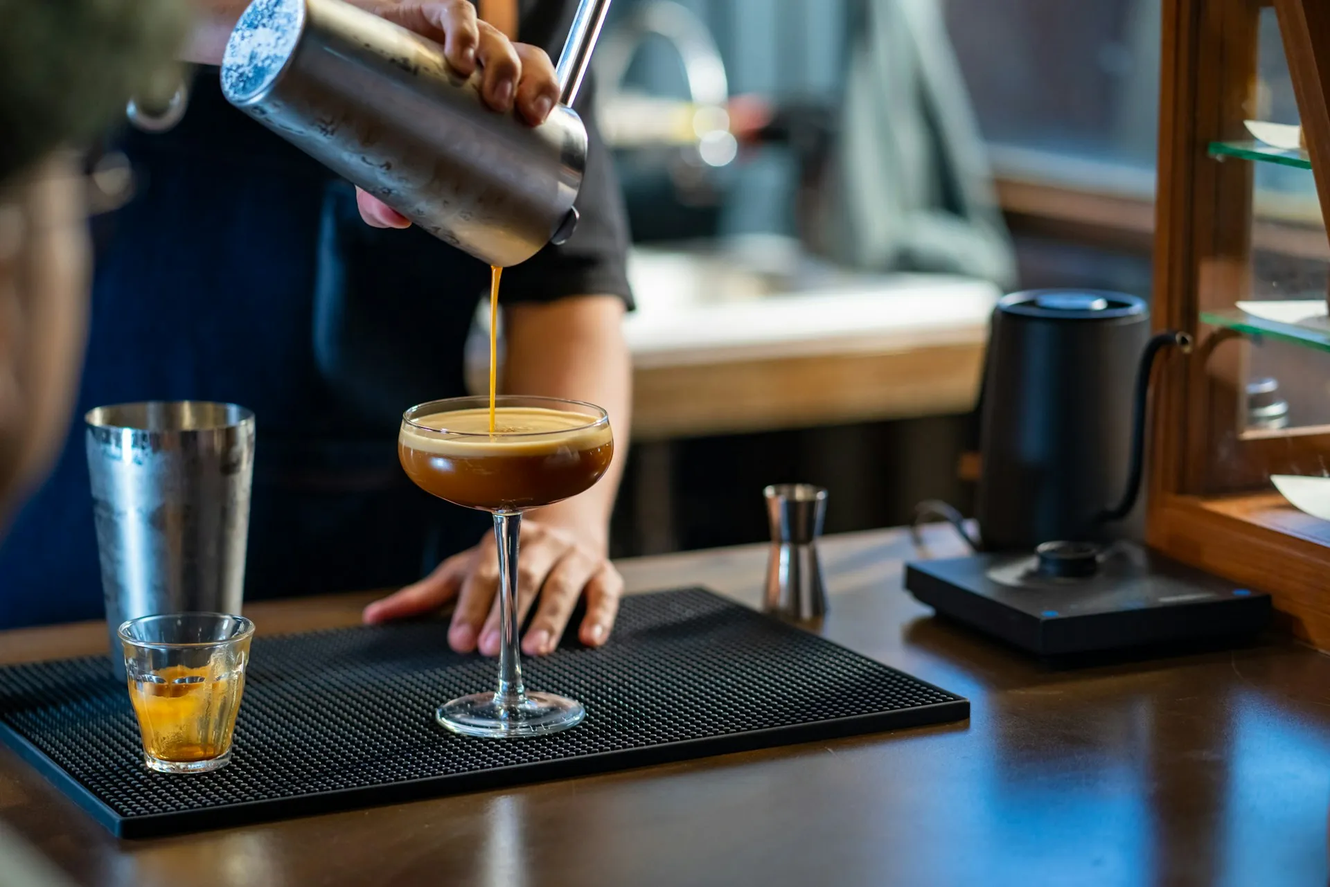 Bartender pouring an espresso martini into a coupe glass