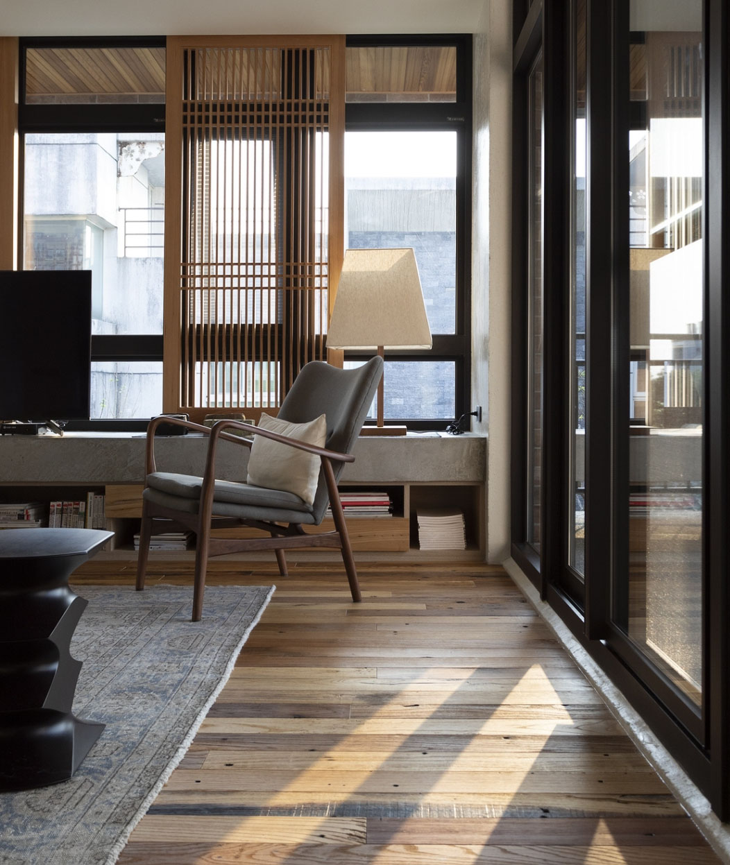 客廳以格柵木窗與玻璃門界定室內外空間，座椅與木地板呼應傳統與現代融合