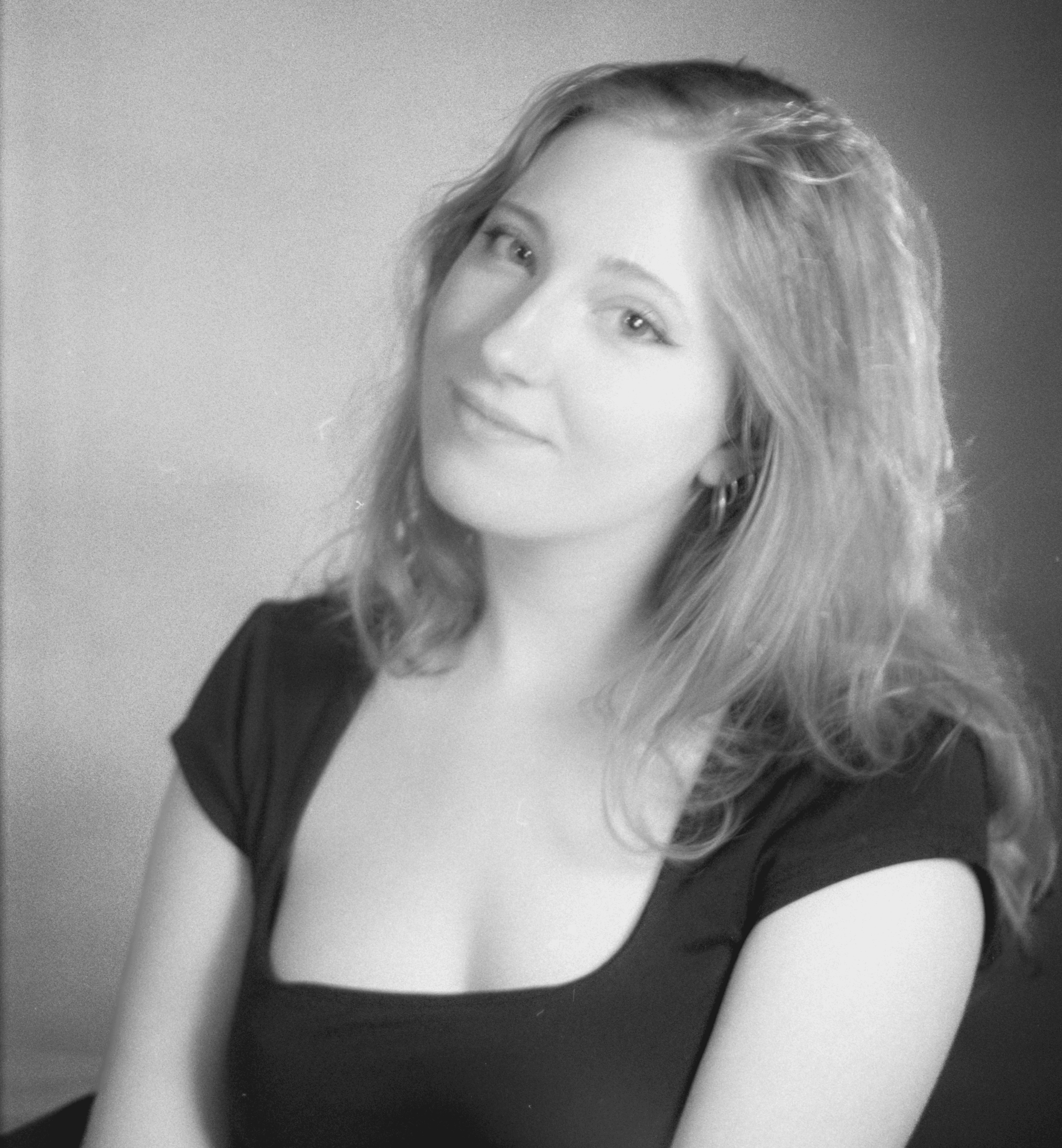 A thoughtful young person with dark hair gazes to the side, captured in soft black and white lighting.