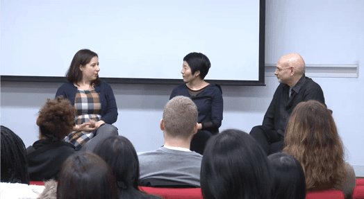 A photo of three persons giving a lecture to some students.
