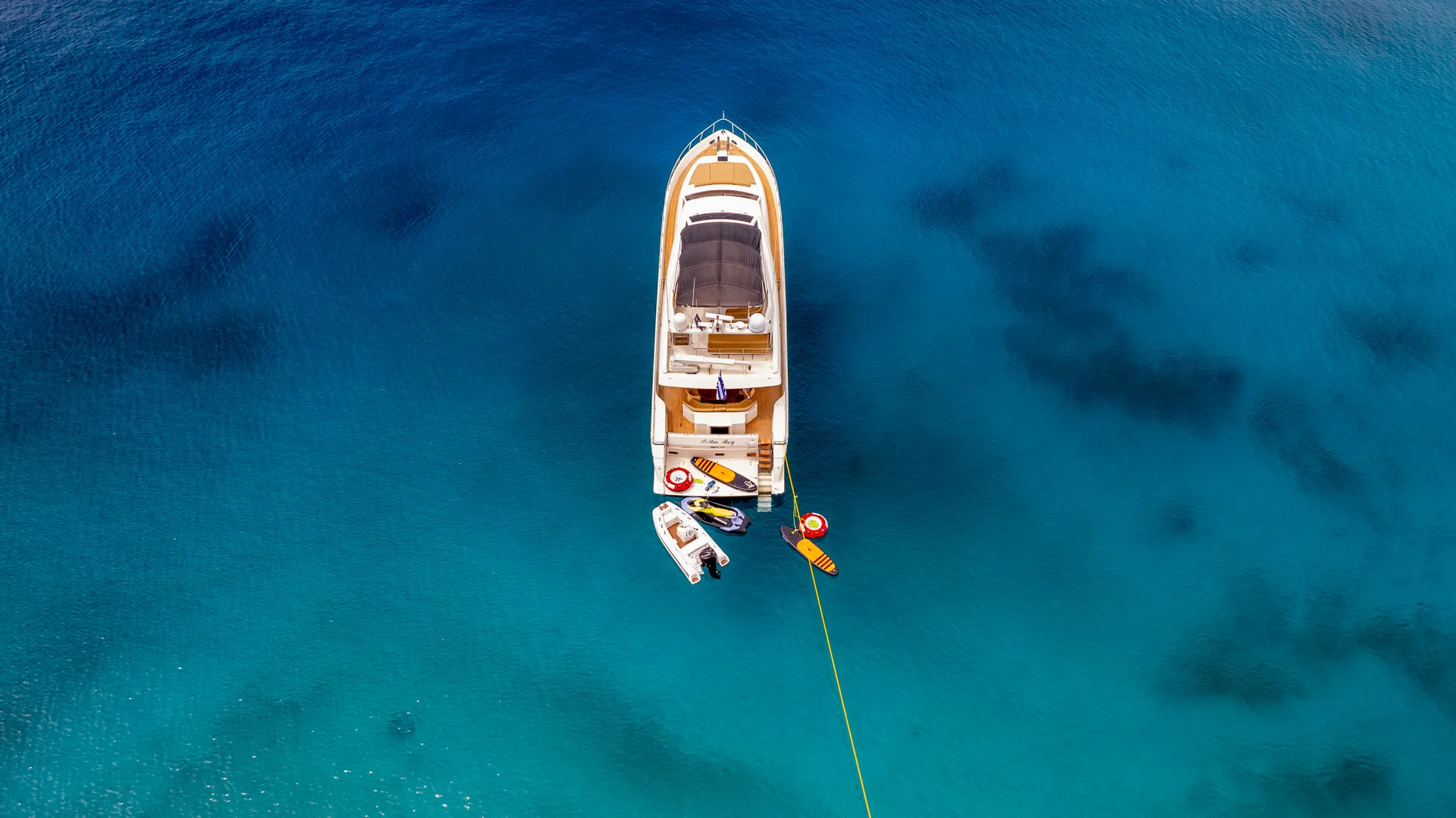 White Rock 36 speedboat with captain at helm cruising calm blue waters near Paros coastline with hills in background.