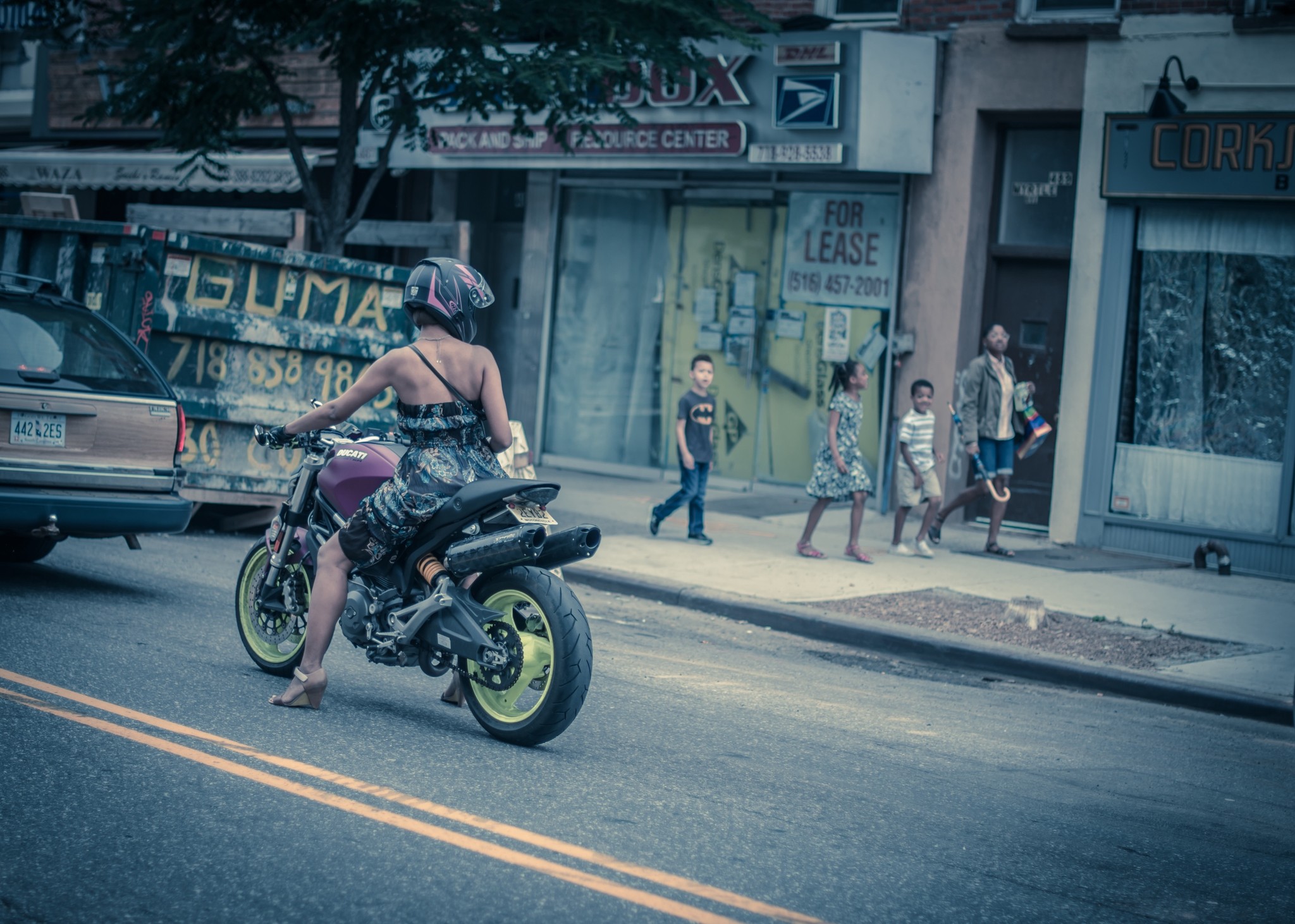 A woman in a dress riding a sport motorcycle on Easter.