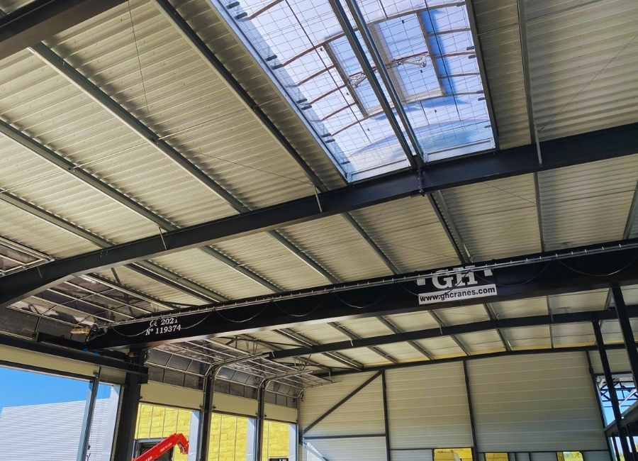 Plafond intérieur avec charpente métallique et panneaux isolants en cours d’installation.