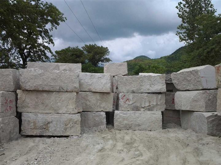 Large stone blocks stacked in a quarry, ready for trimming and cutting by the portable wire saw machine, illustrating the preparation phase of stone processing.