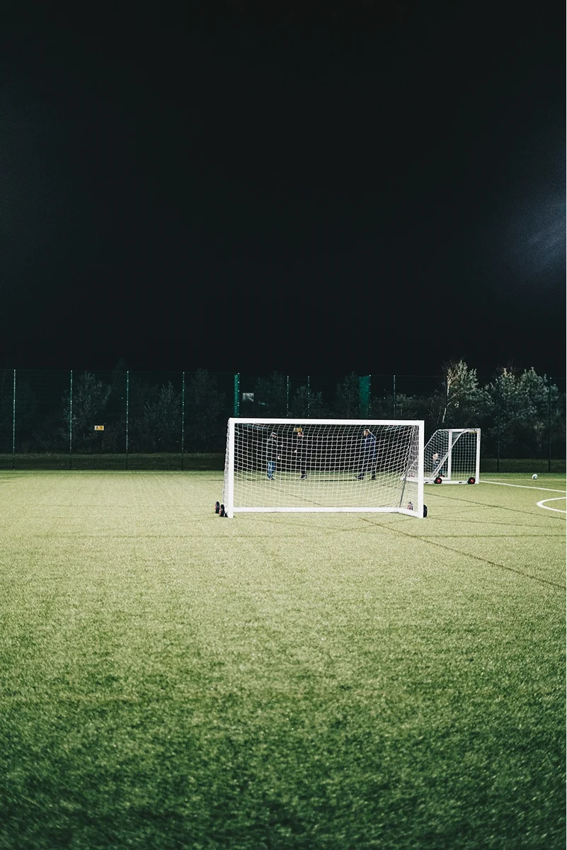 Small soccer goals on an artificial-turf field at night