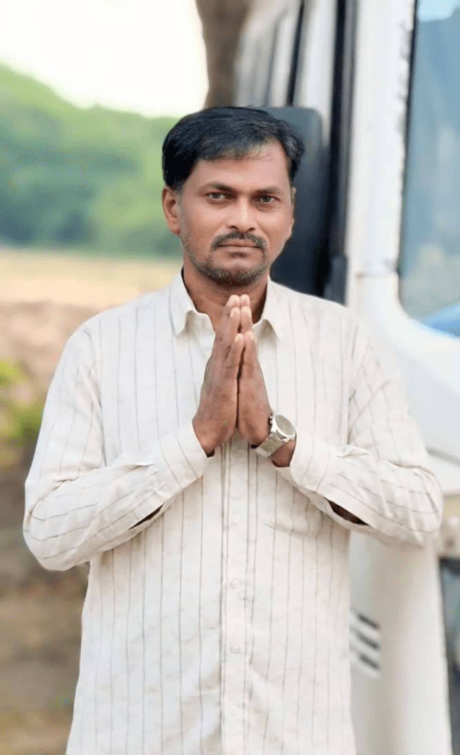 Smiling female therapist with short gray hair, wearing a brown top and a purple shawl, surrounded by a cozy background.