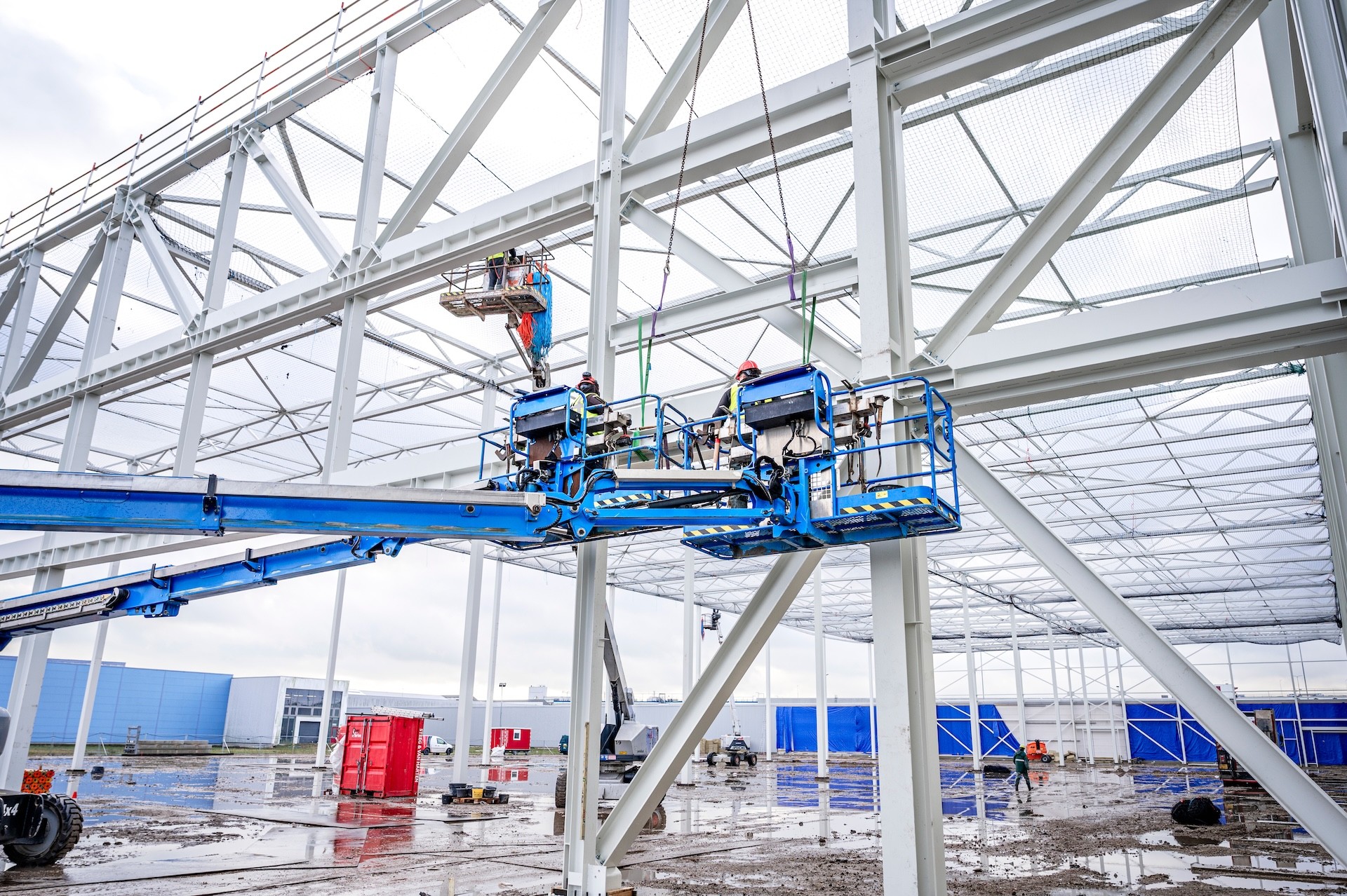 Blauwe hoogwerkers met montagemedewerkers erop- Steeg en van Harten