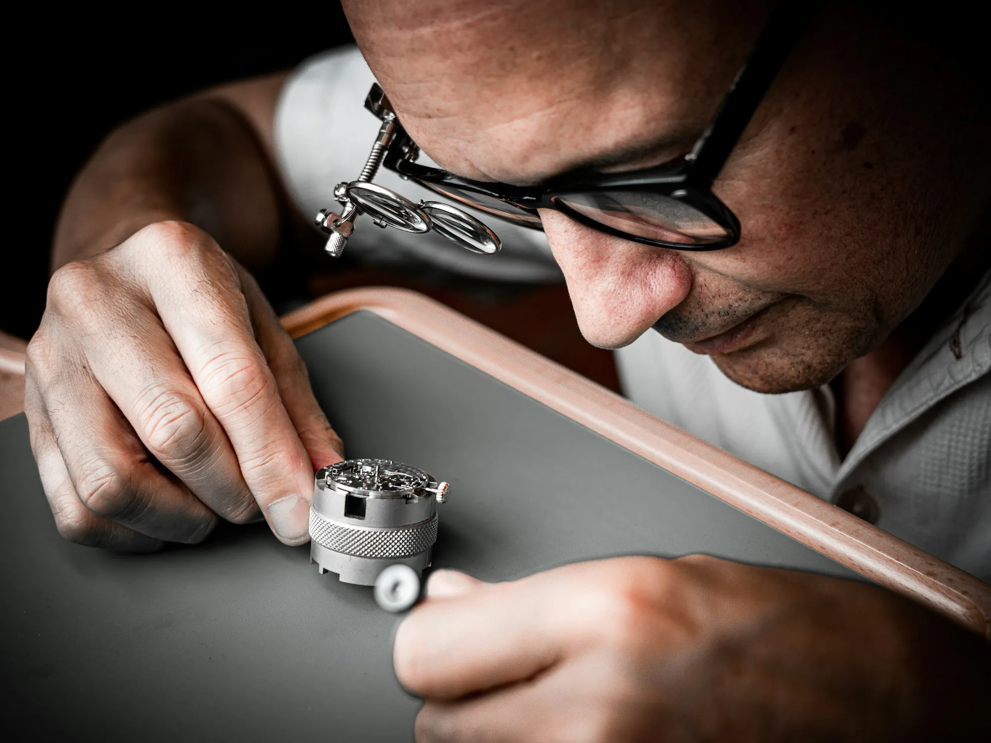 Watchmaker using a loupe to inspect a watch movement