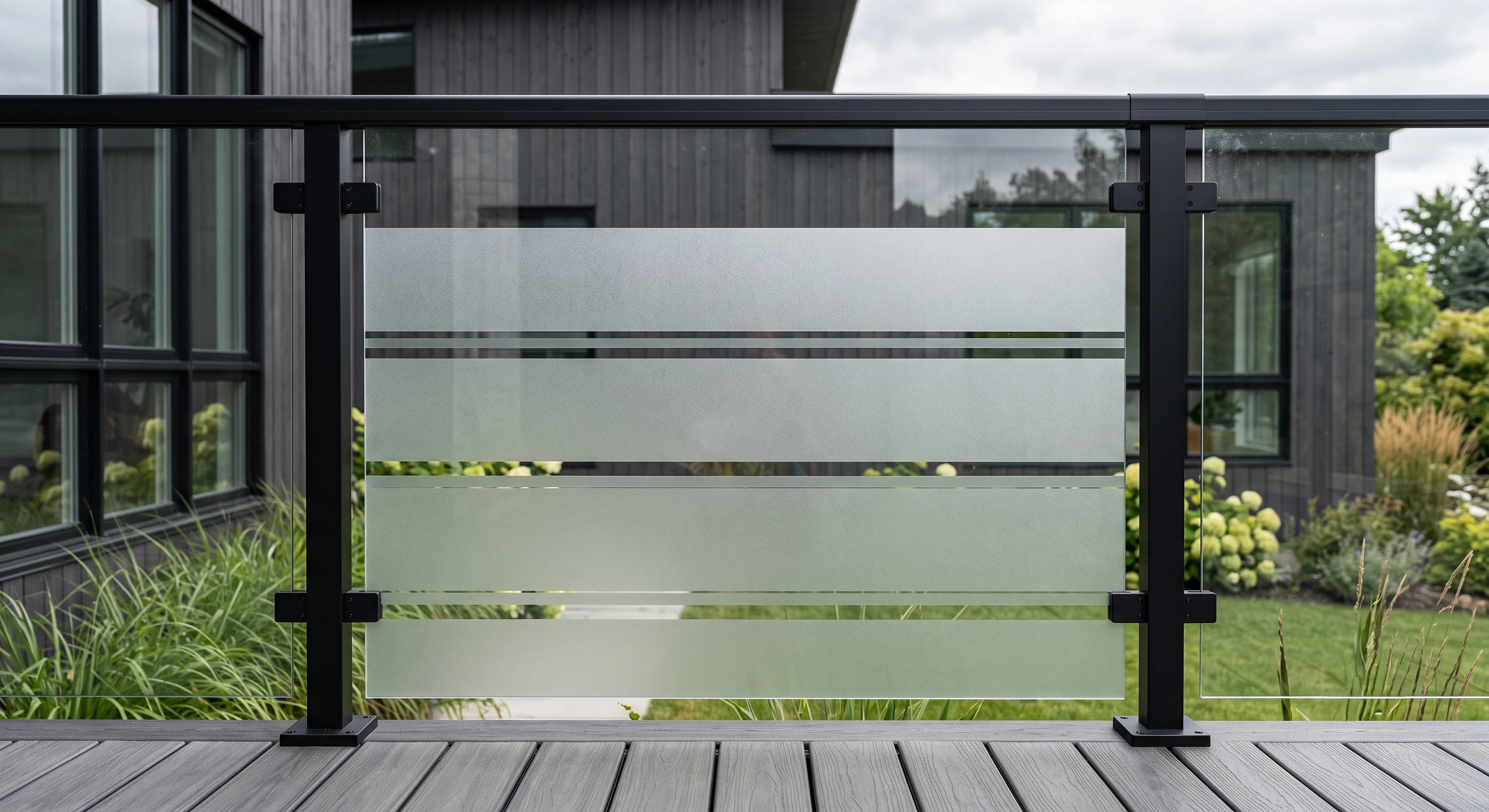 Sandblasted glass railing panel with a banded pattern between slim black aluminum posts
