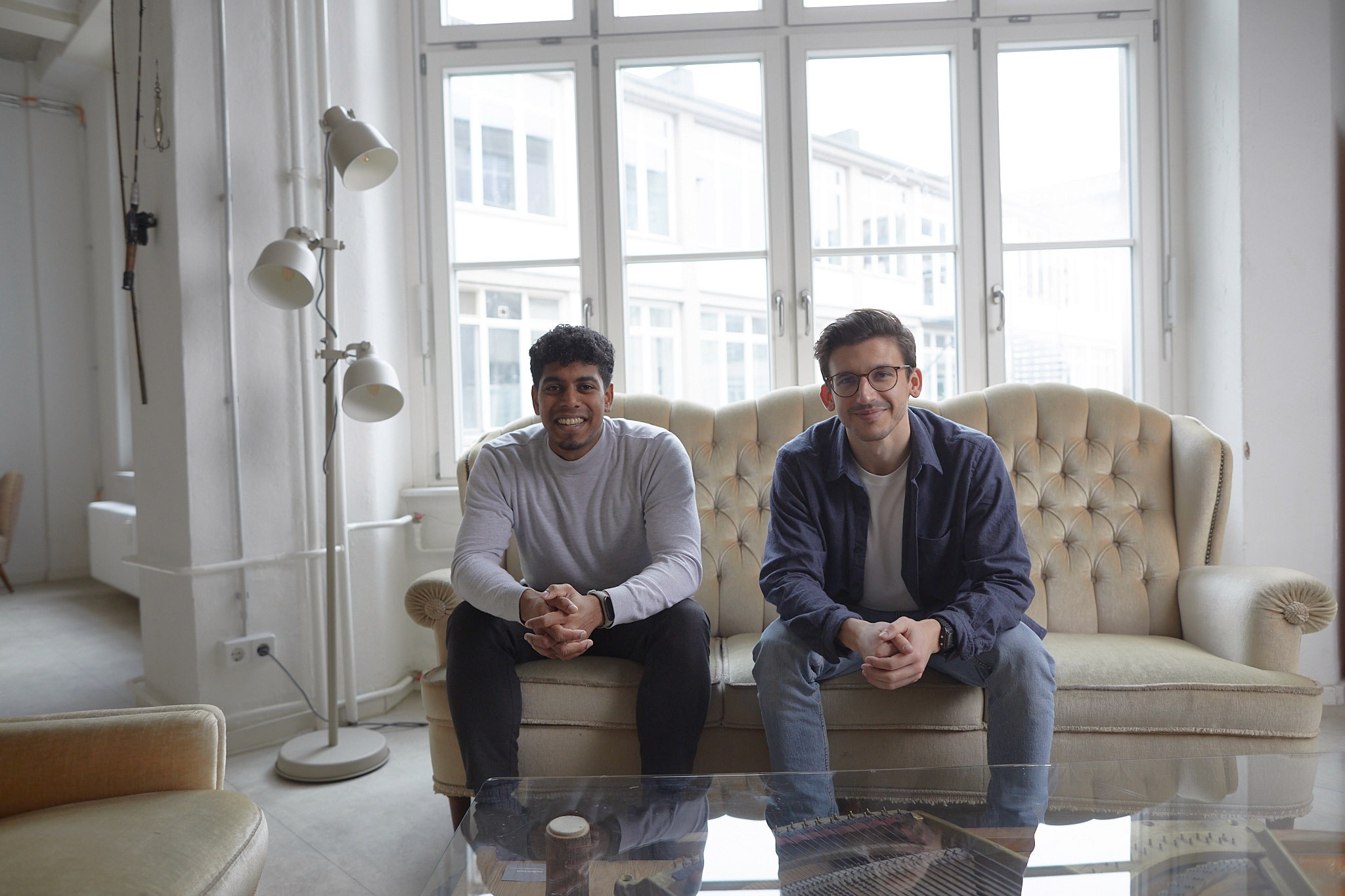 CaseWhen Consulting founders, Sajagan Thirugnanam and Austin Levine, sitting on a sofa in a bright, modern office, representing their expertise as Power BI consultants.