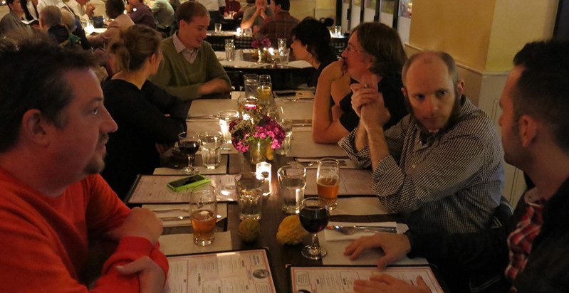 A photo of a group of people sitting at a table, facing each other, in a restaurant.