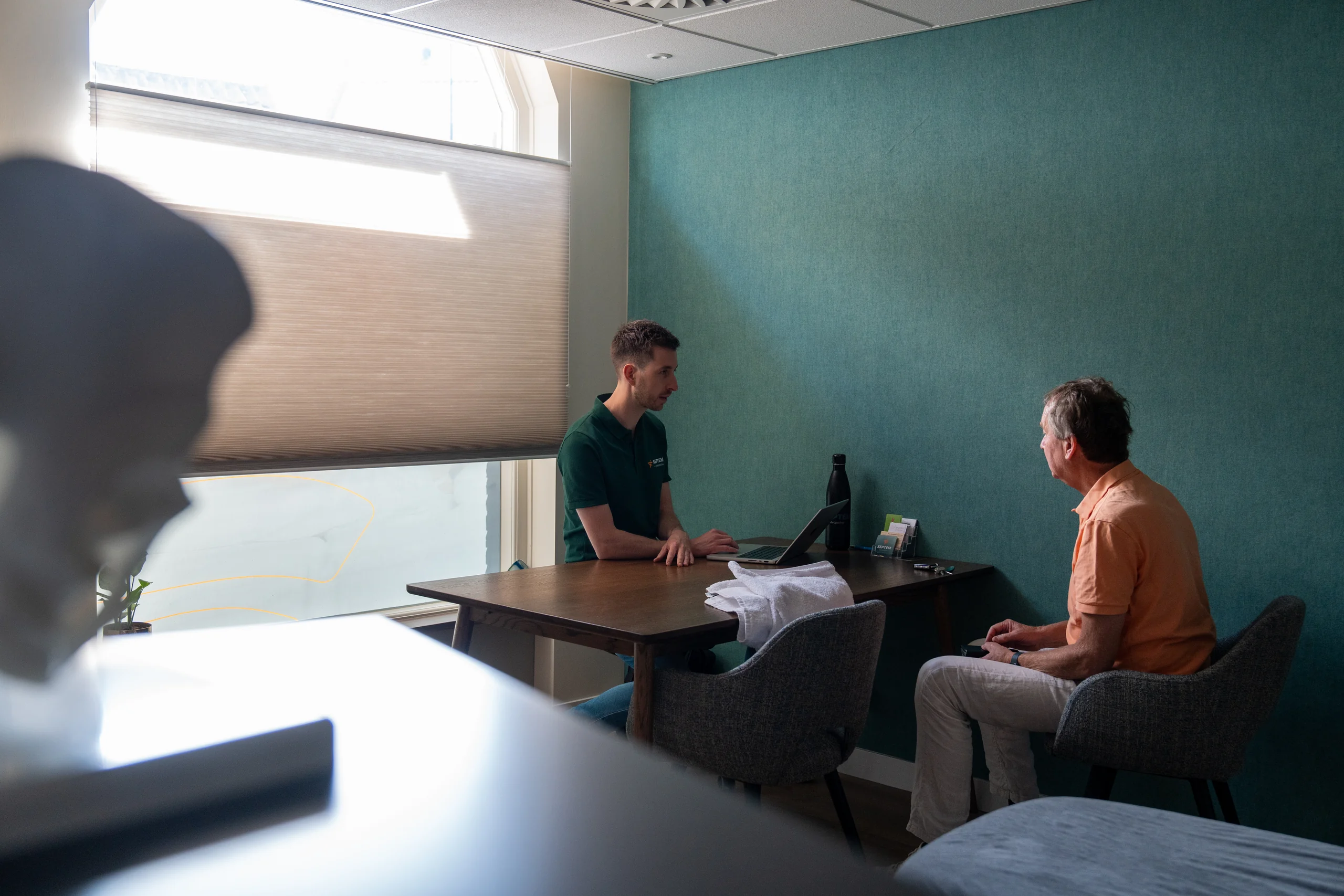 Osteopaat in gesprek met een volwassen patiënt