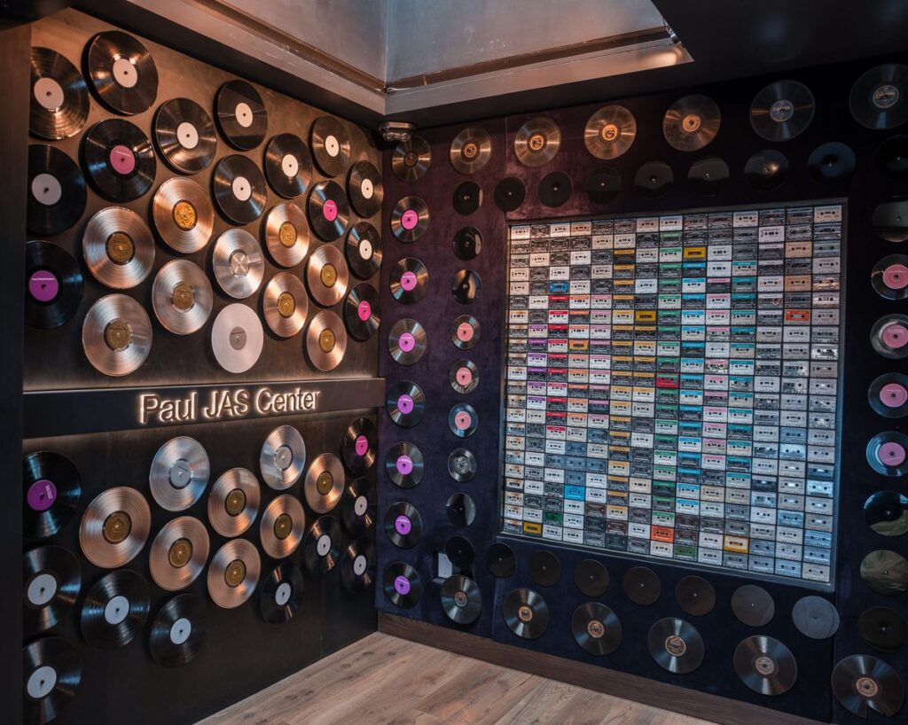 aul JAS Center entrance hallway with vinyl record wall display, platinum discs, and illuminated perforated LED ceiling panel