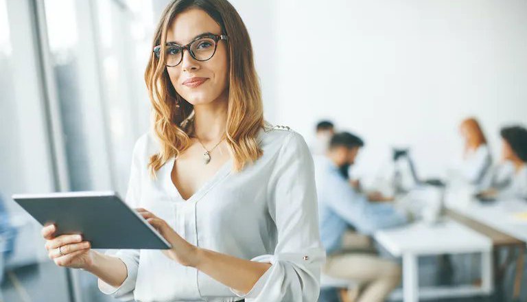 Figura feminina posando para foto em frente a uma equipe de marketing trabalhando