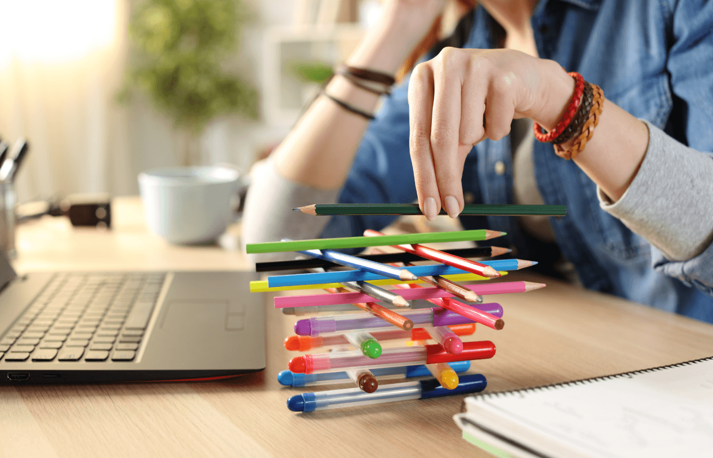 student plays with pens sitting on a desk at home