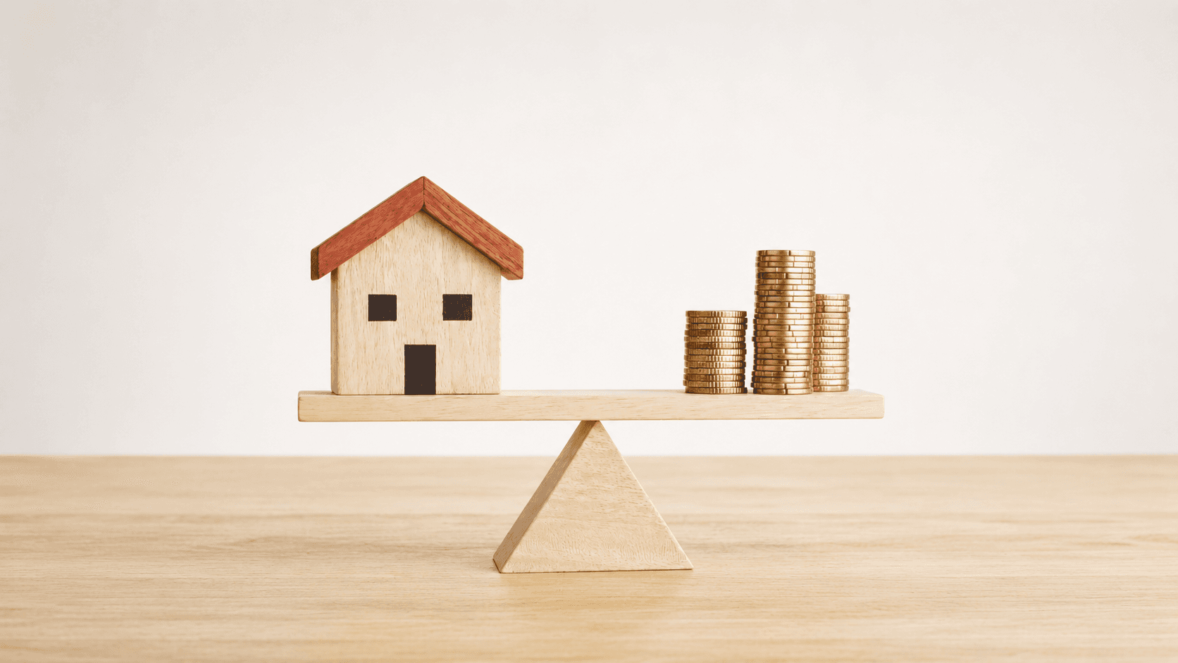 A balance scale with a house on one side and coins on the other, symbolizing the value of property versus money.
