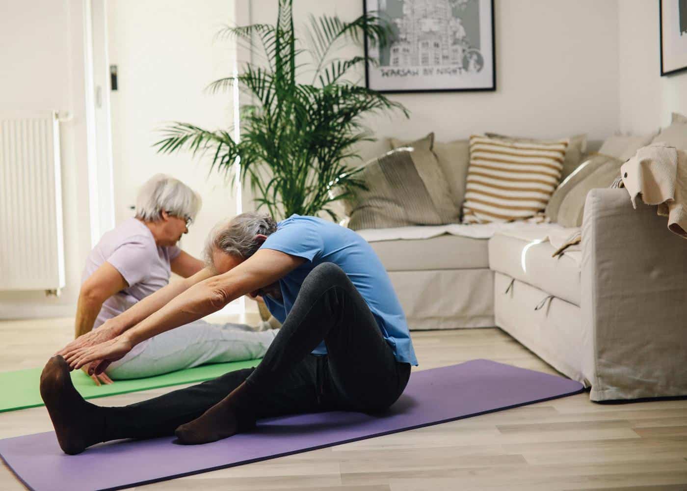 Two elderly people stretching on yoga mats