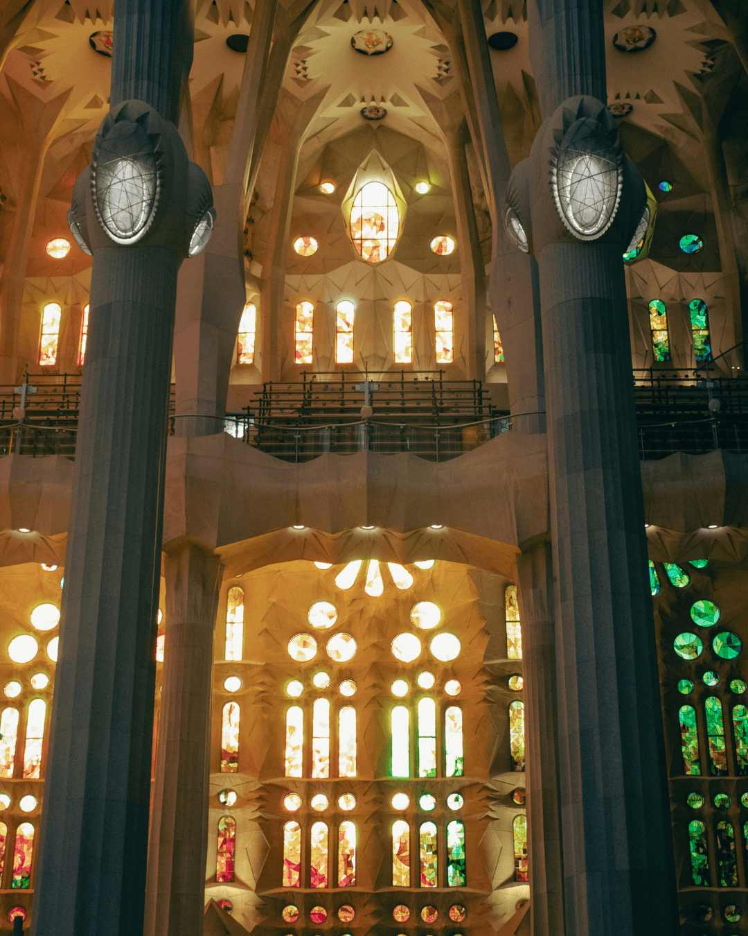 Stained glass windows inside the Sagrada Família, warm and cool tones side by side.