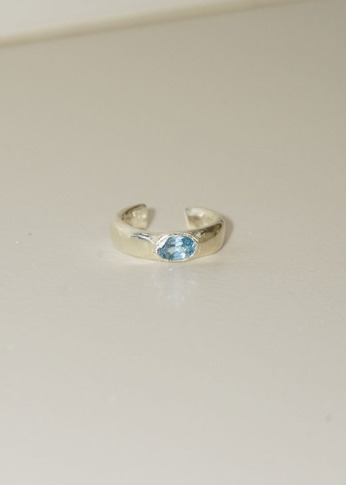 Silver ring with a blue gemstone on a beige background