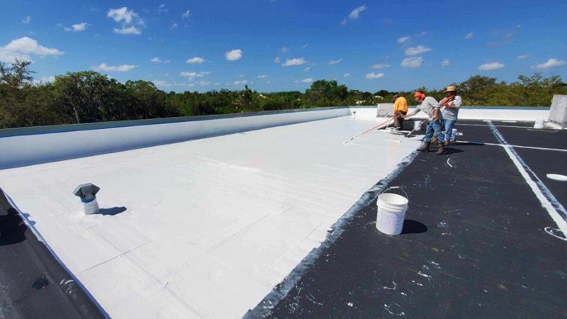 Large commercial building with a bright white acrylic roof coating, reflecting sunlight to improve energy efficiency and protect against weather damage.