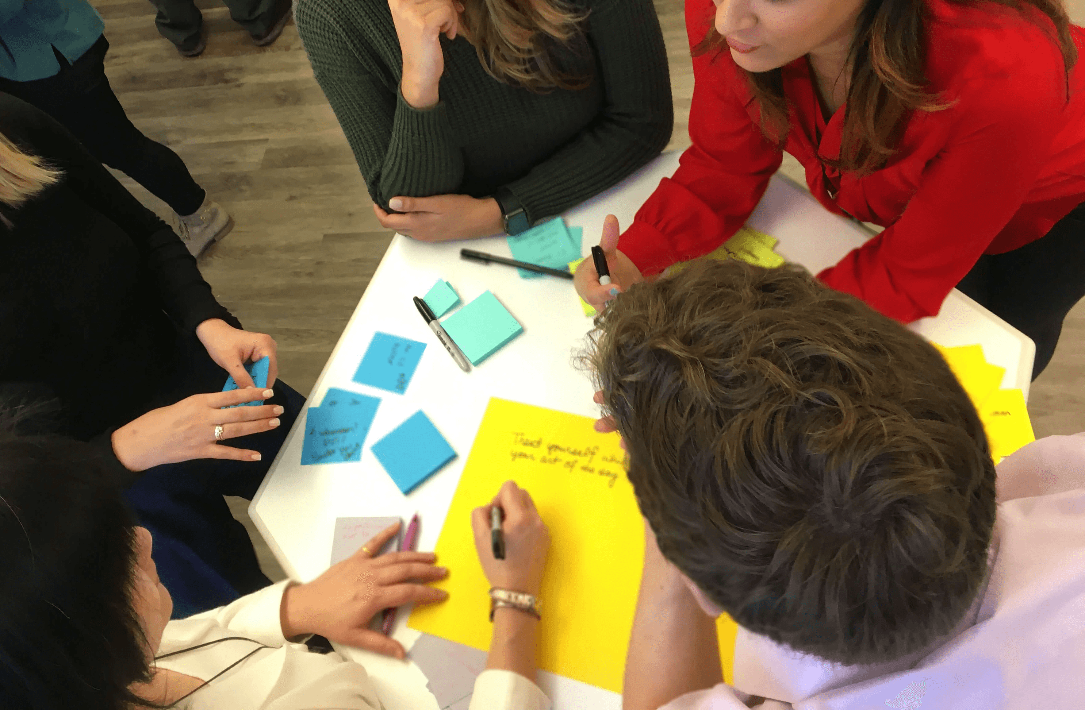 Group of young professionals collaborating around a table with colorful sticky notes during a brainstorming workshop