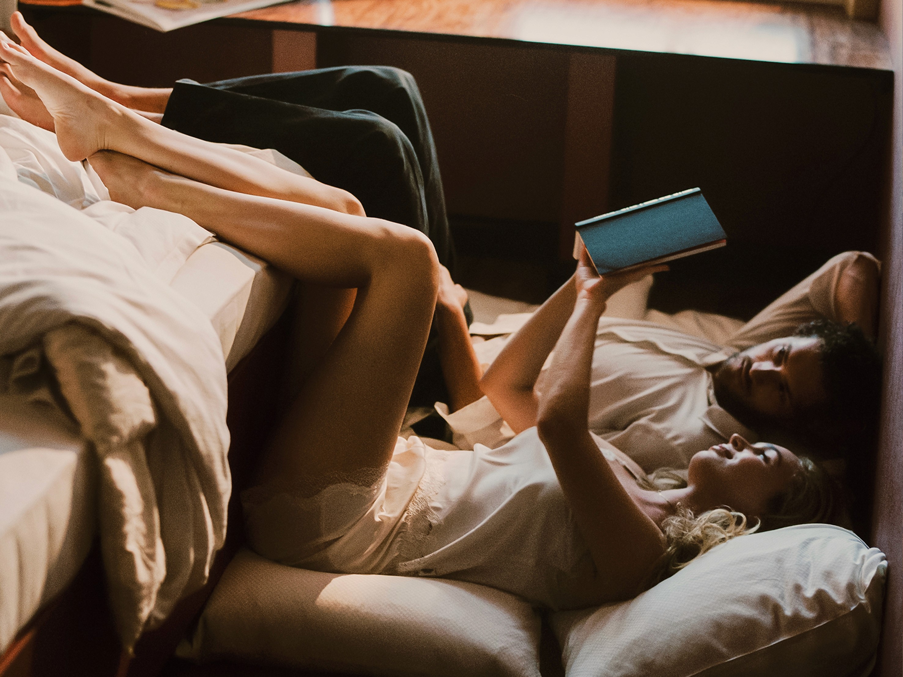 Two people lounging on a bed at the Companion Vienna, looking at a book.