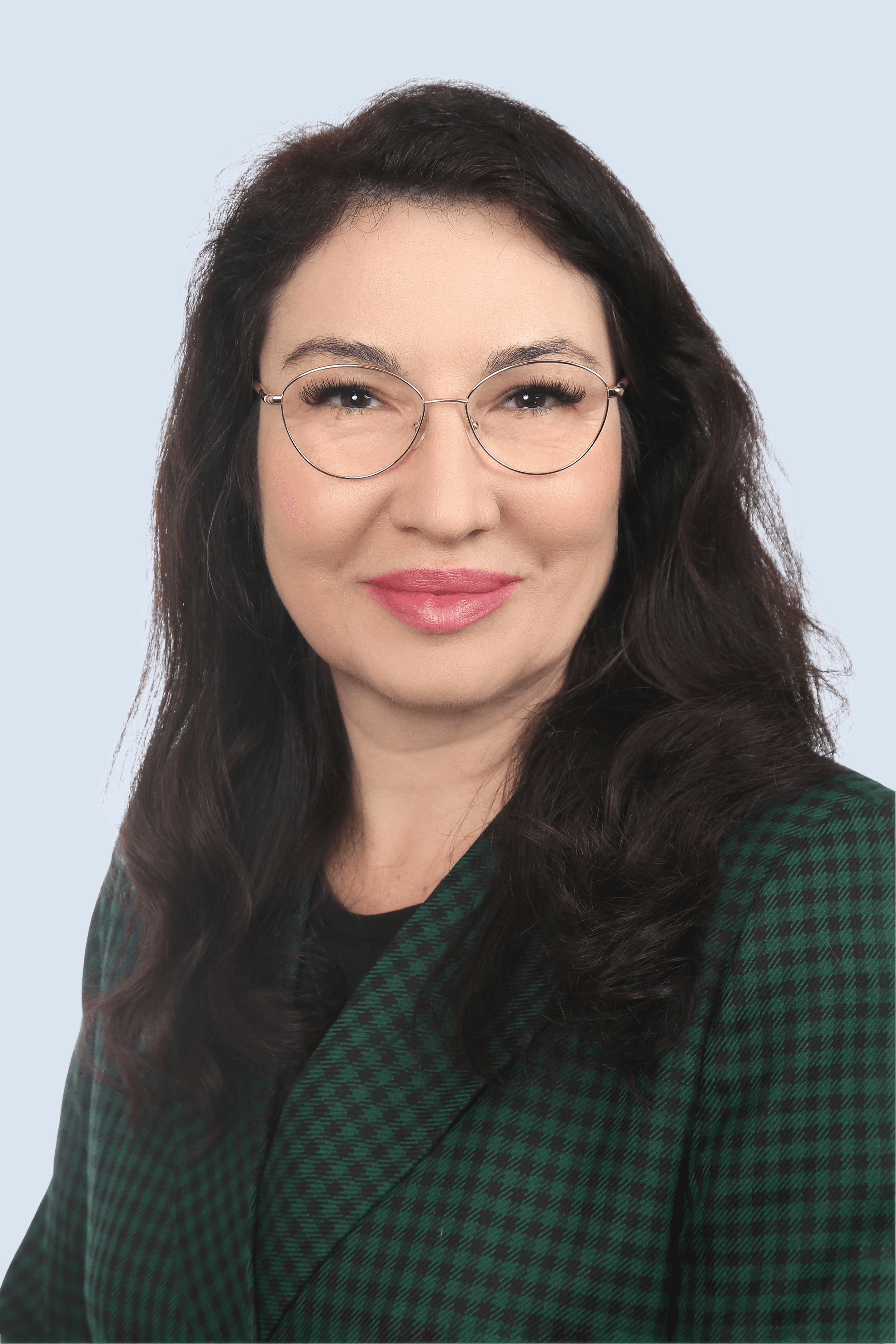 Tatiana Imhof. Professionelles Business Portrait einer Frau mit Brille und dunklem Haar. Freundlicher Blick, grüner Blazer, neutraler Hintergrund.