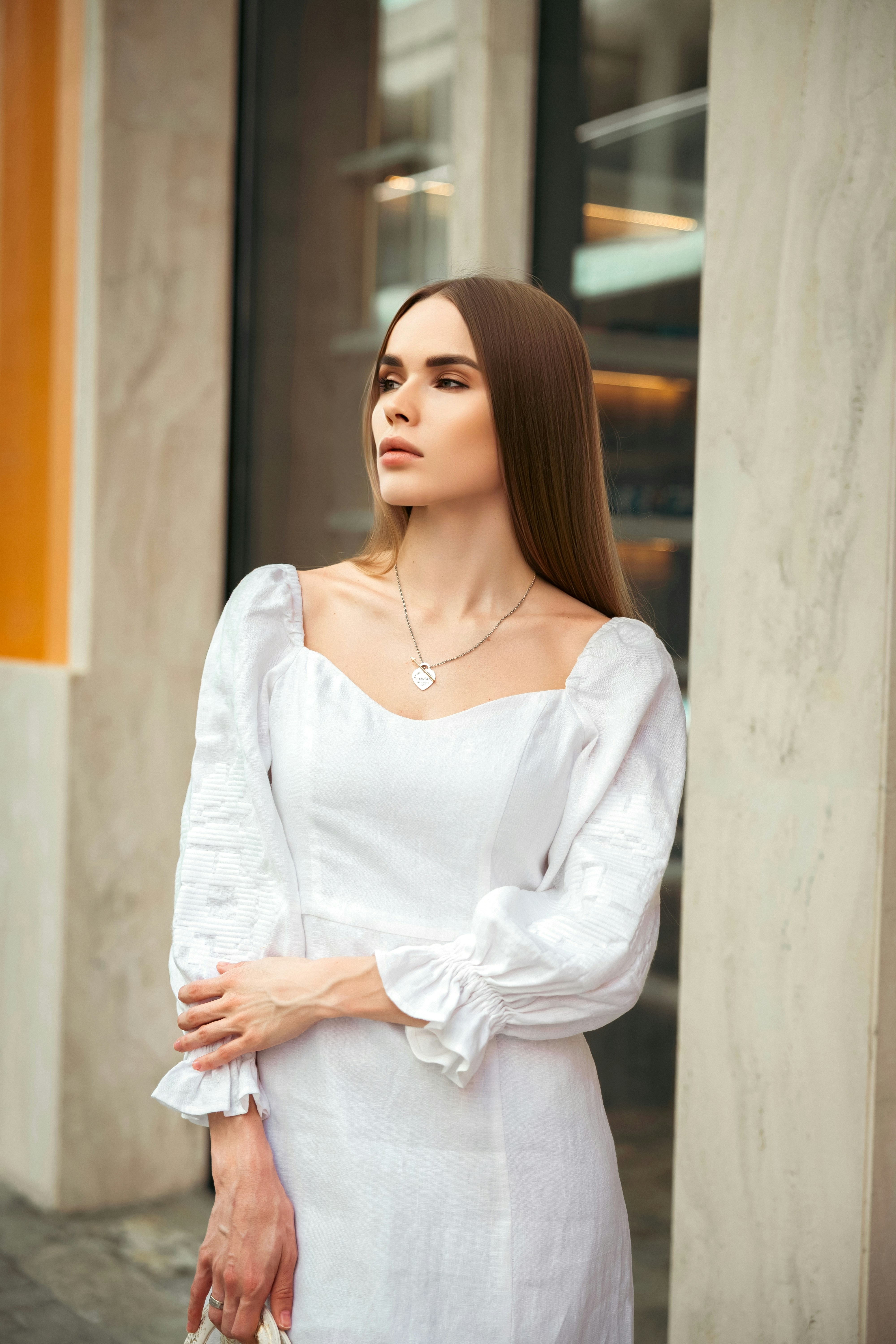 A woman poses gracefully in a white dress.