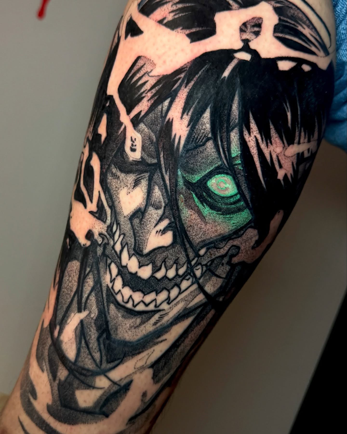 A grayscale anime-style tattoo of a character with spiky hair and a headband, holding a kunai.  The tattoo is on someone's forearm.
