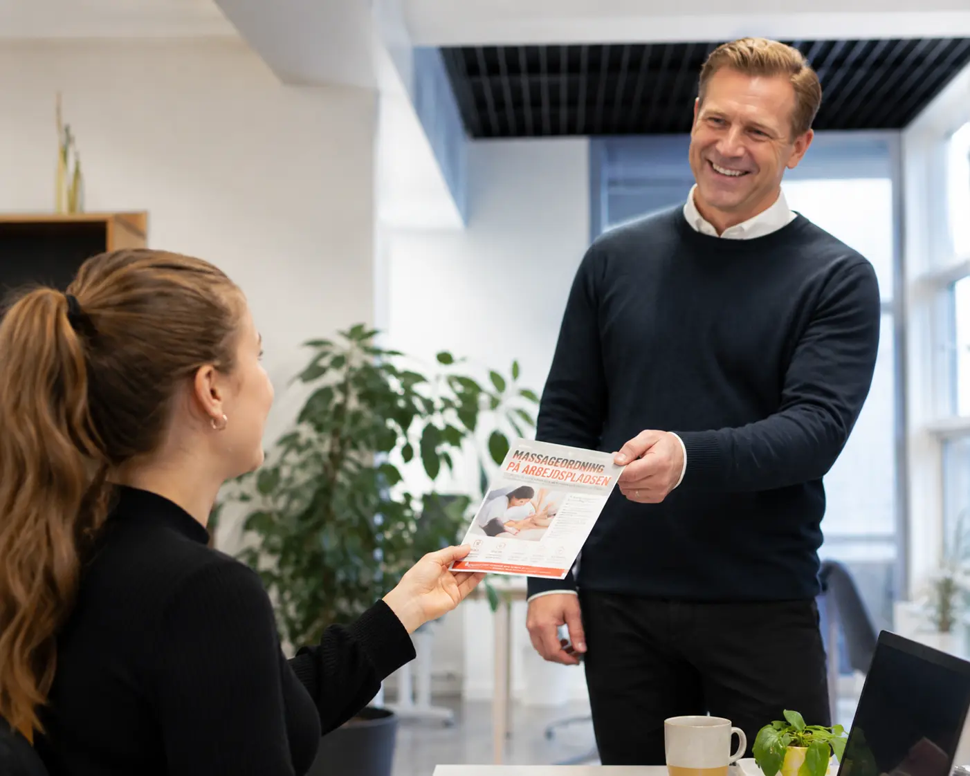 HR-medarbejder modtager information om RedMinKrop firmamassageordning på arbejdspladsen med fokus på trivsel, fysisk velvære og mindre smerter.