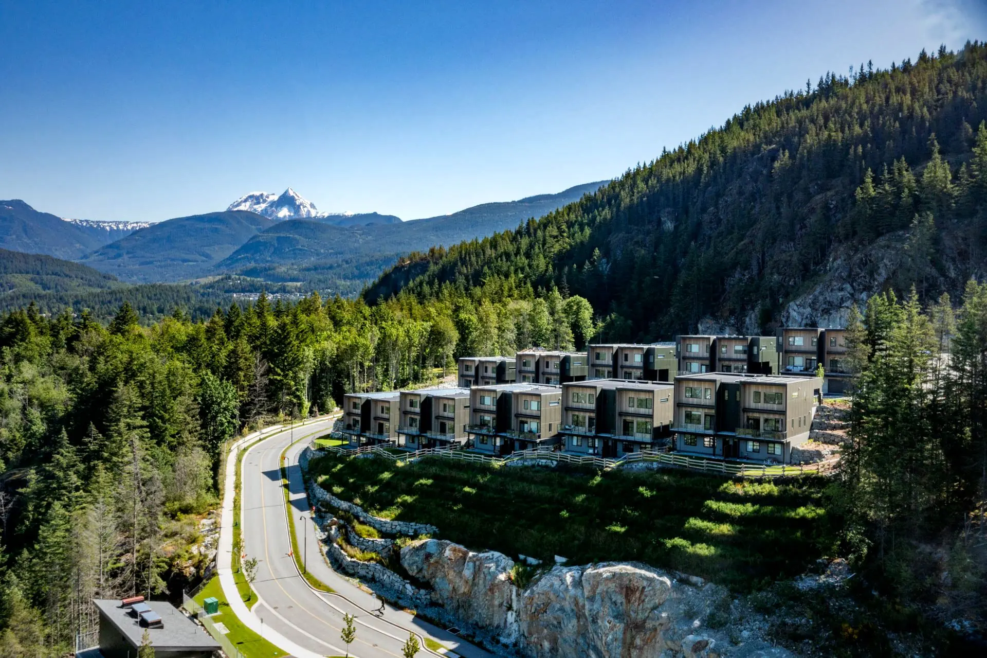 Aerial view of the Finch Drive high-performance duplexes in Squamish surrounded by trees and mountains.