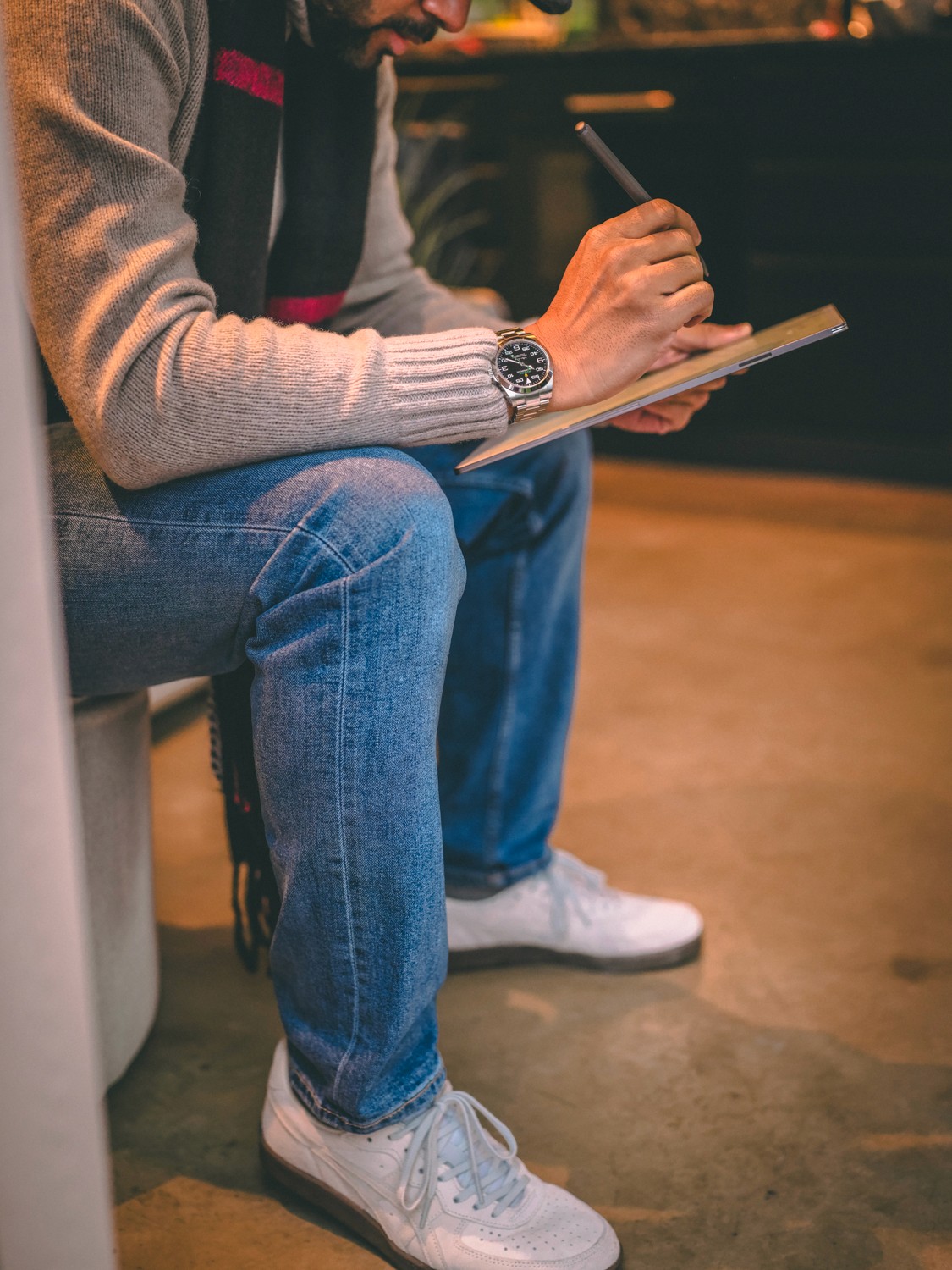 Woman with wavy hair holding a large bouquet of red flowering branches in warm light.
