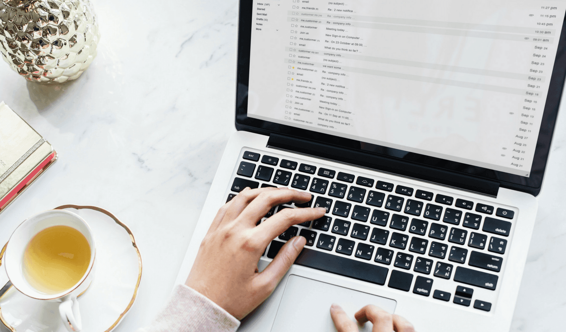Woman using a laptop with a cup of tea next to her