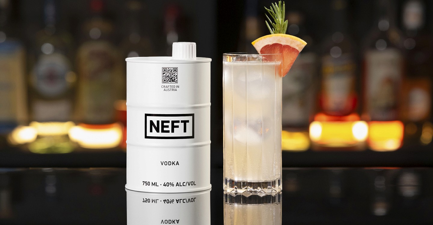 A NEFT Barrel and a glass of Halston on a bar counter.