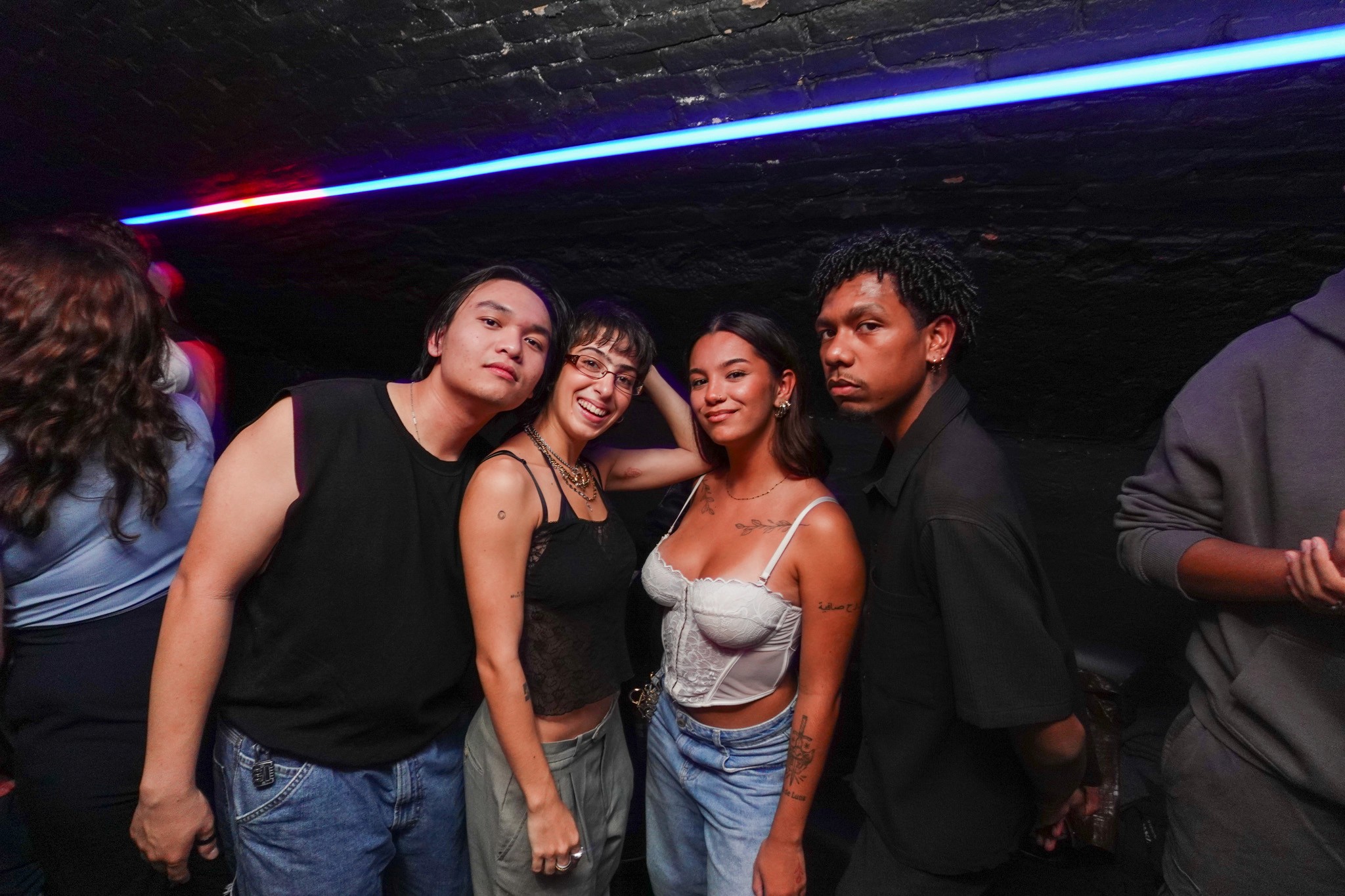 Group of young international partygoers posing together inside a crowded underground bar during a bar crawl in Nice with neon ceiling lights dark club atmosphere and confident nightlife energy representing the diverse social vibe of a French Riviera night out