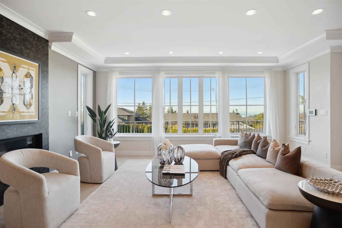 Bright and spacious living room with large windows, modern furniture, and a serene view outside.