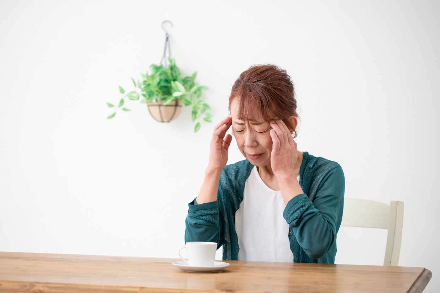 椅子に座って頭を押さえる高齢の女性