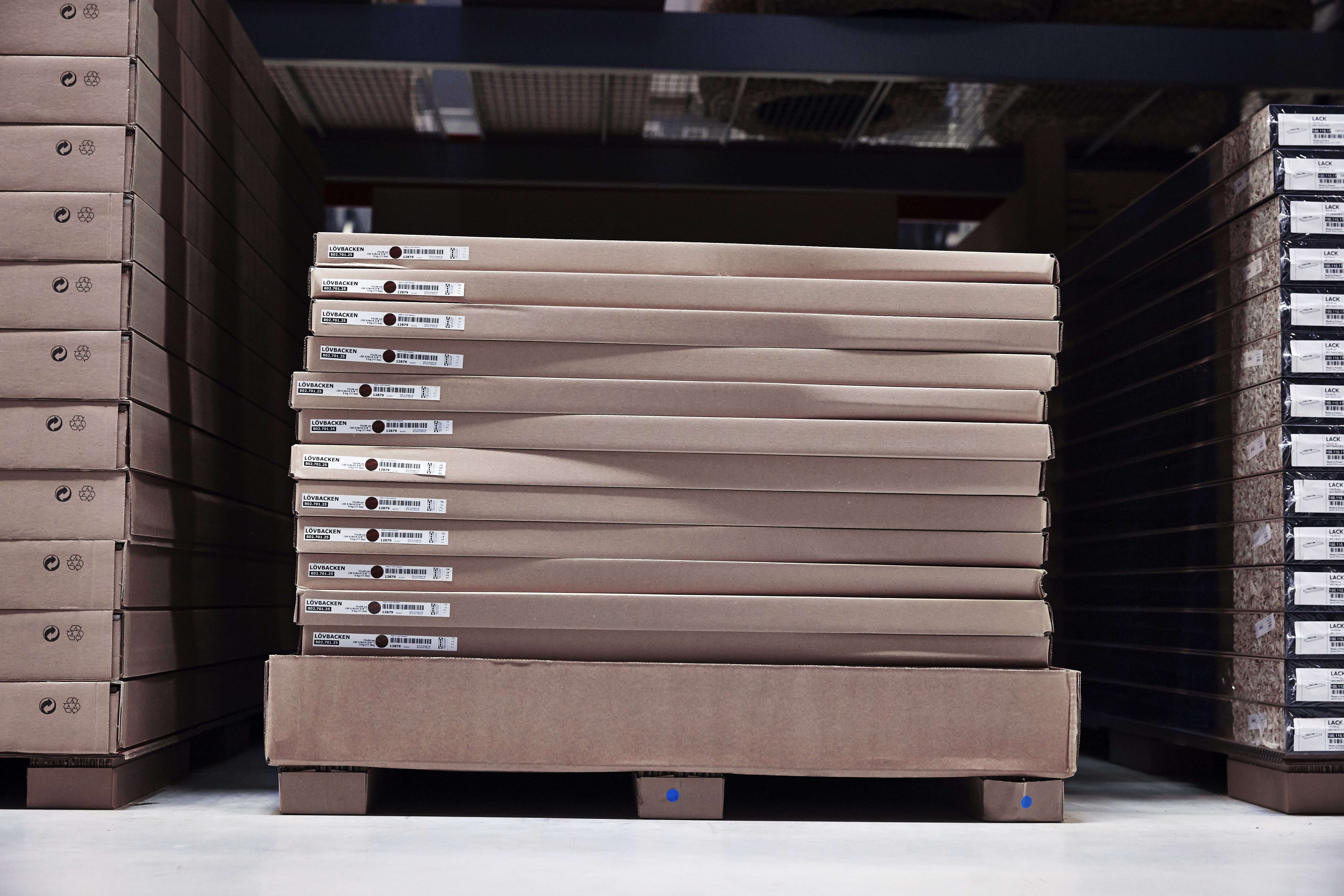 Close-up of IKEA flat-pack cardboard boxes stacked on a pallet. This image illustrates the logistics-driven design and functional packaging that define the brand's identity and global supply chain efficiency.
