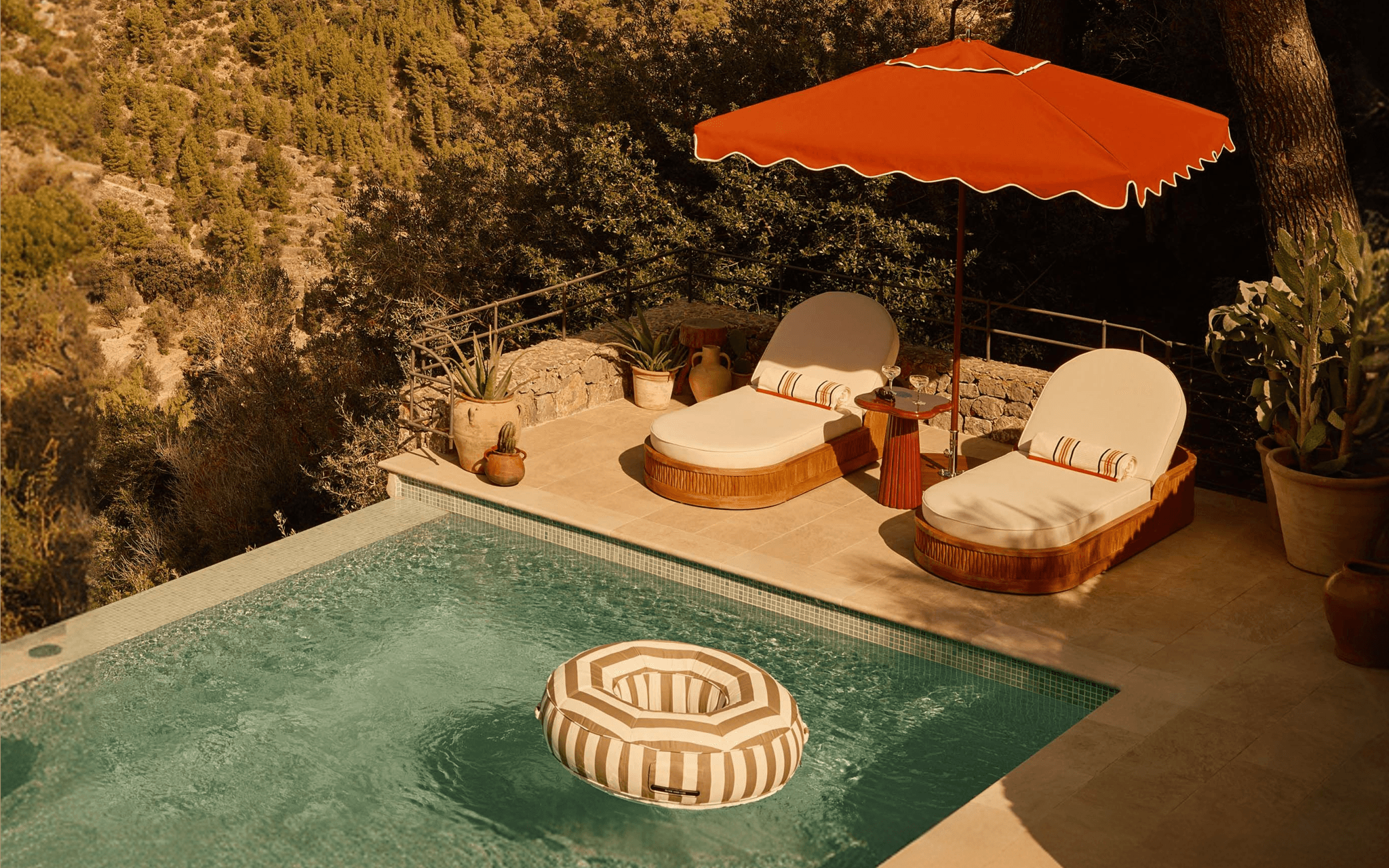 Oliver James Lilos x Soho Home Babington Stripe luxury pool float in custom Sunbrella Panama weave, floating in a hilltop infinity pool overlooking the Mediterranean coastline of Deià, Mallorca