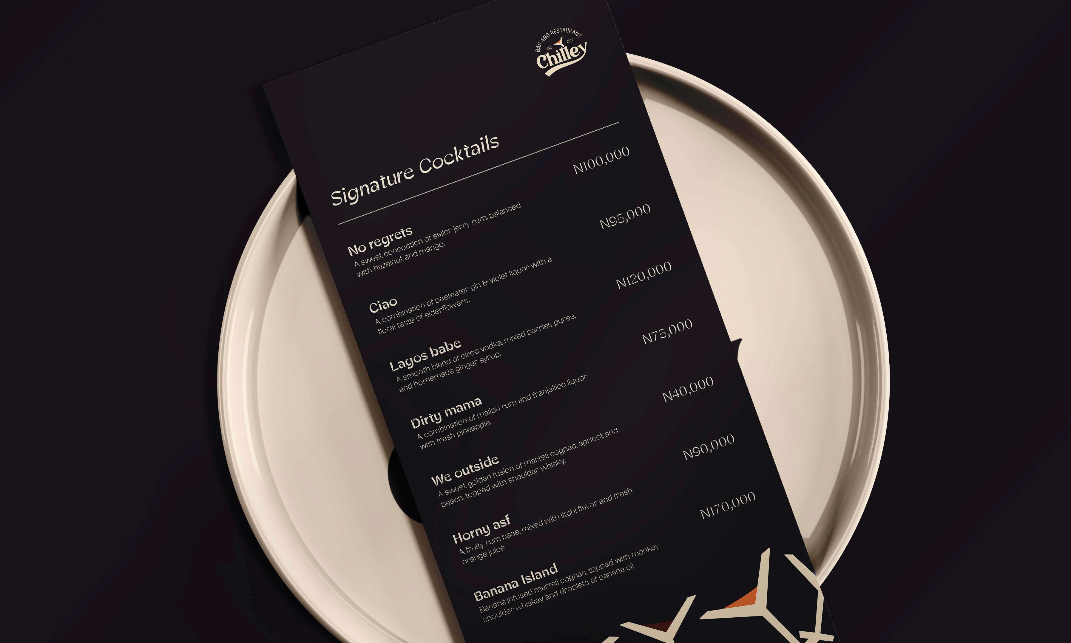 A dark-themed cocktail menu resting on a white plate, featuring a list of signature drinks and prices.