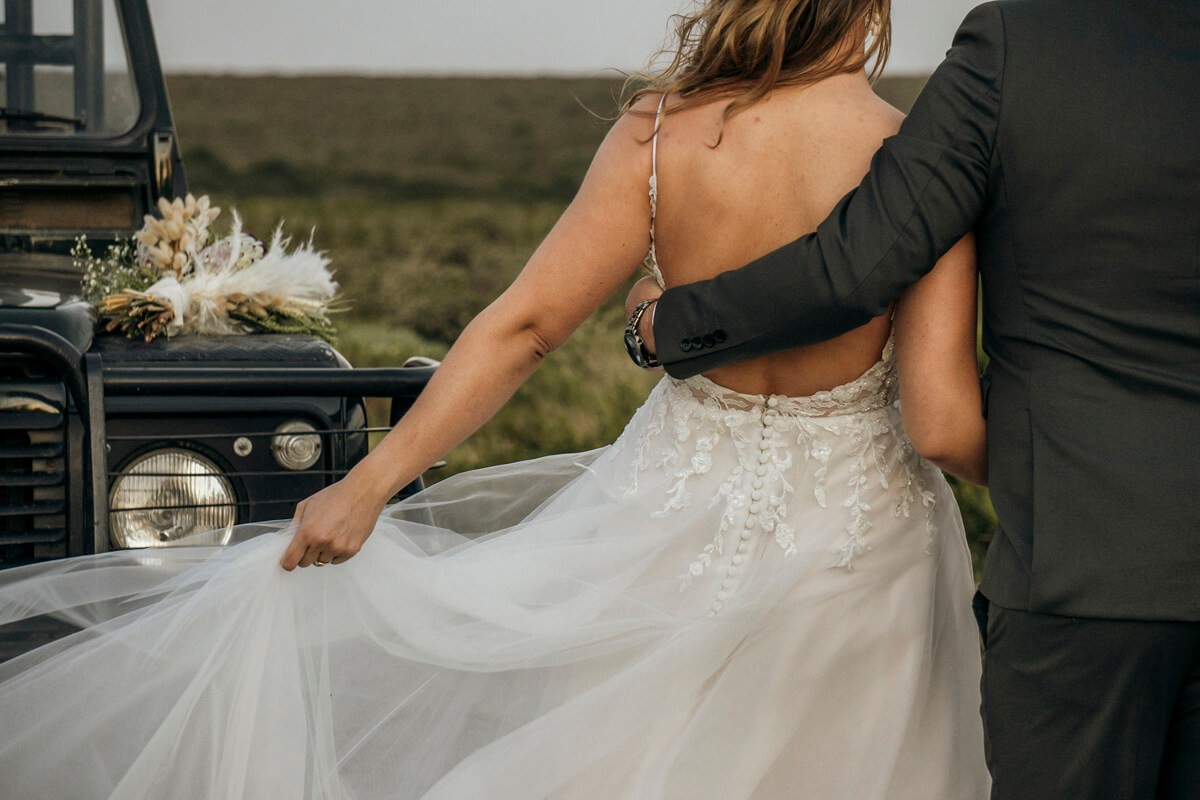 Bride and groom standing beside safari game drive vehicle at Lombardini