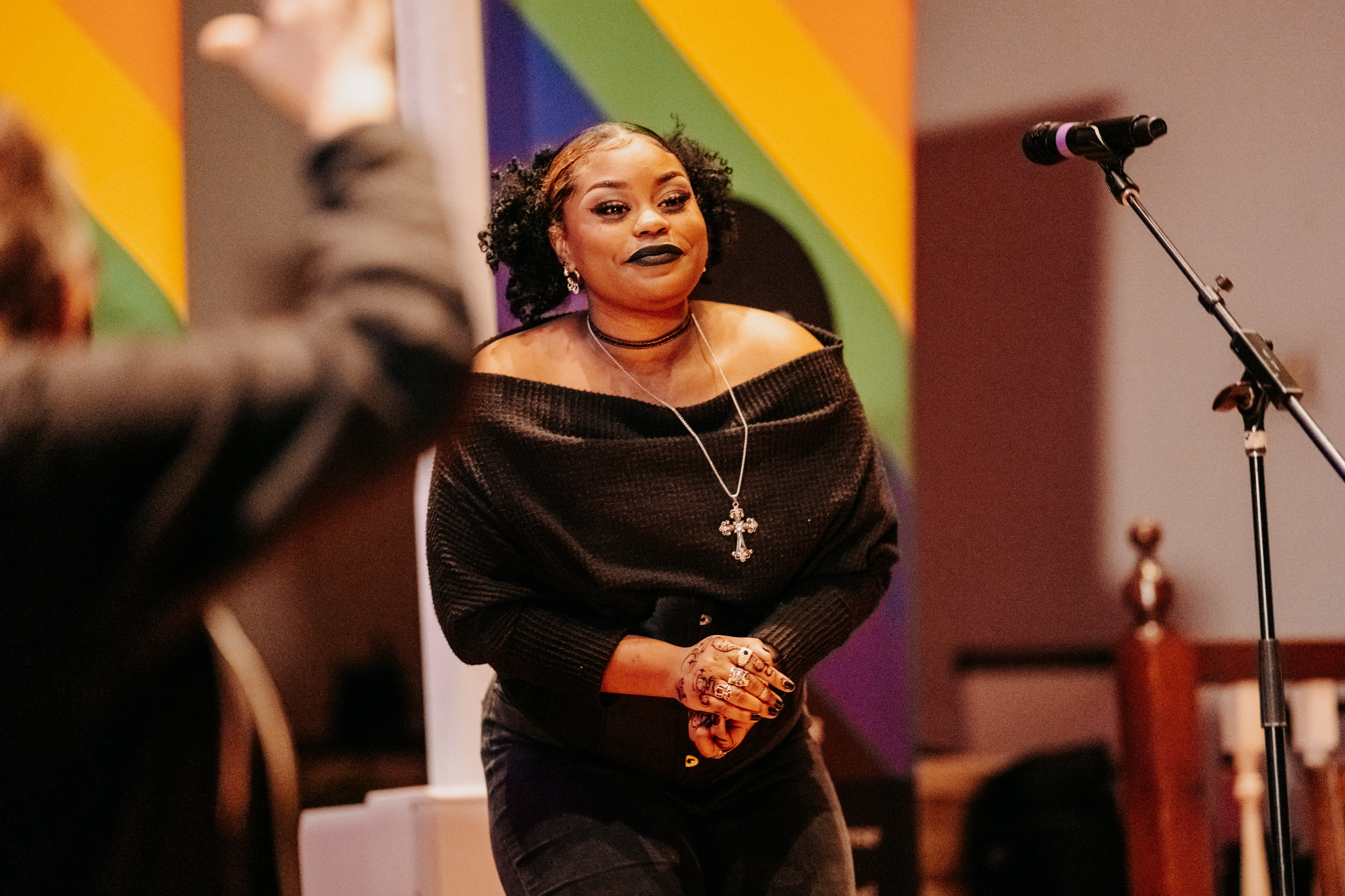 Performer standing on stage during the Queer Open Mic (QOM) hosted by be; community in Bridgewater, Massachusetts.