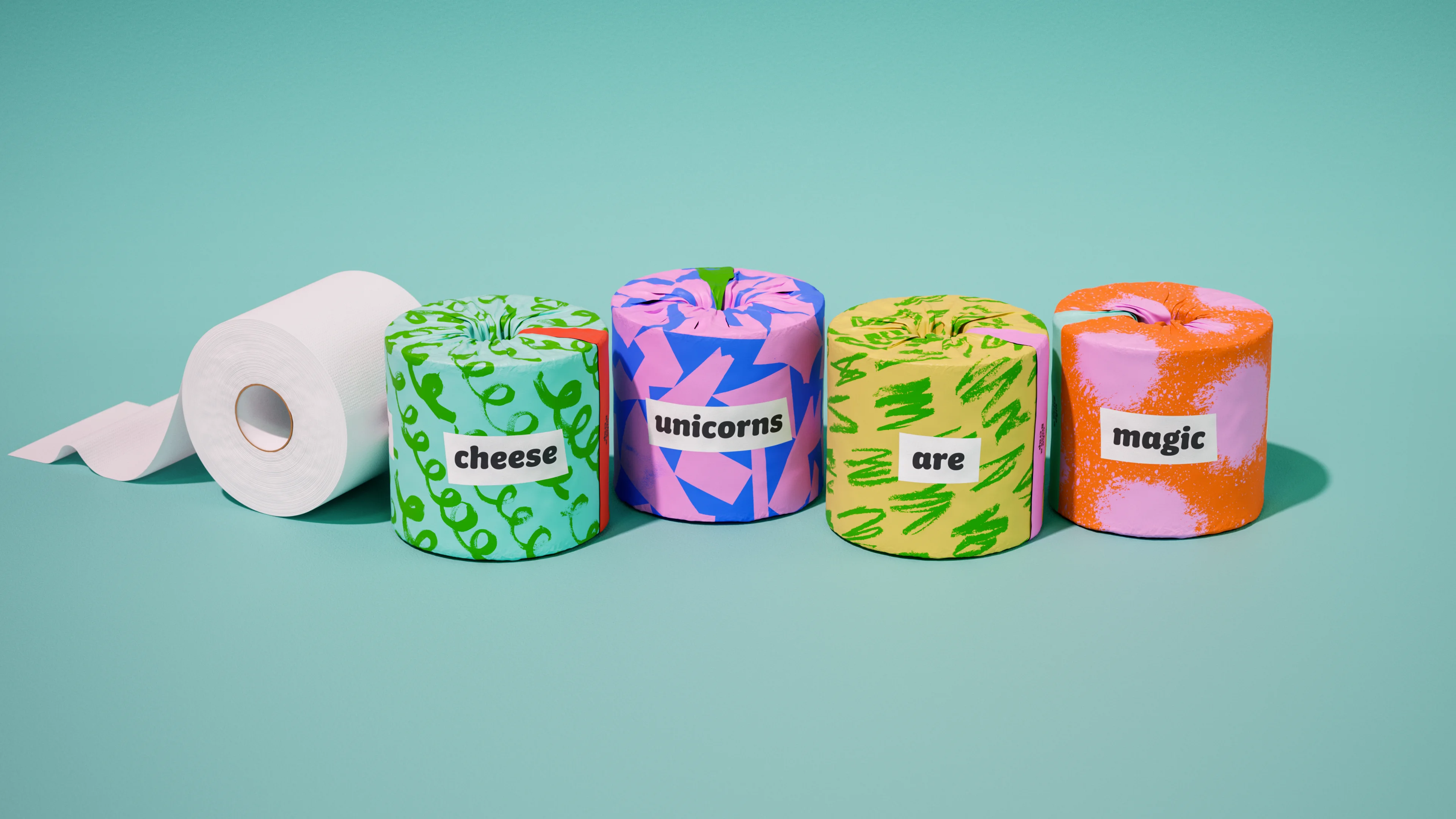 Four Who Gives A Crap Poetry rolls labeled cheese, unicorns, are, magic in a row beside an unwrapped white roll on a teal background