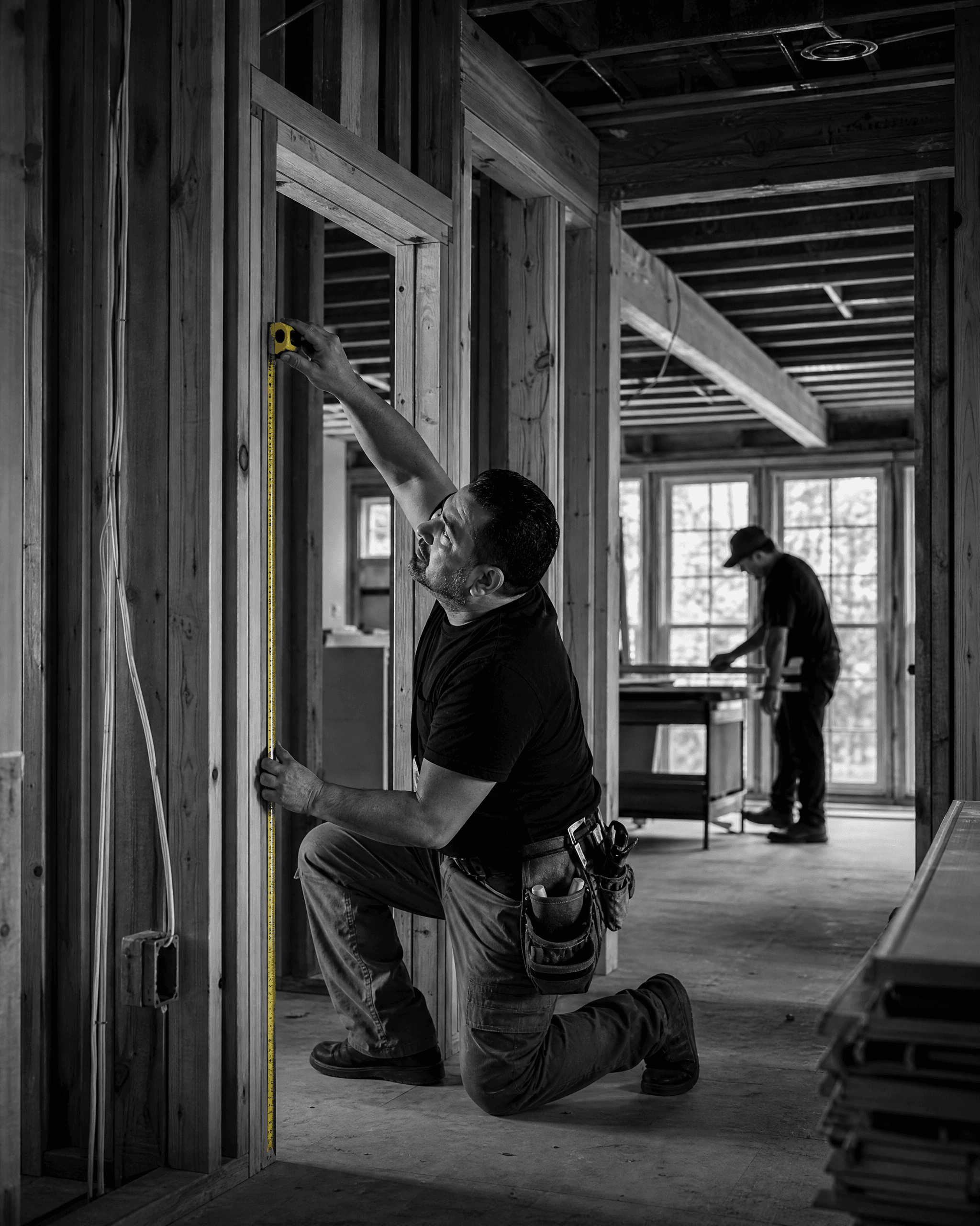 Remodeling professional measuring a framed doorway during active residential construction.