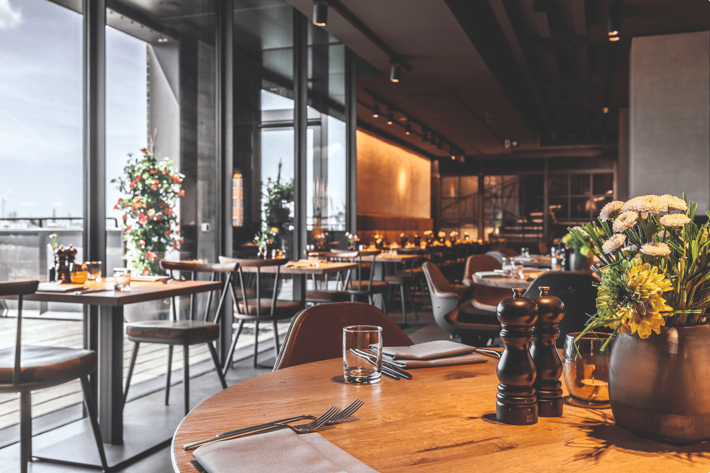 Restaurant interior with tables, chairs, and floral arrangement.