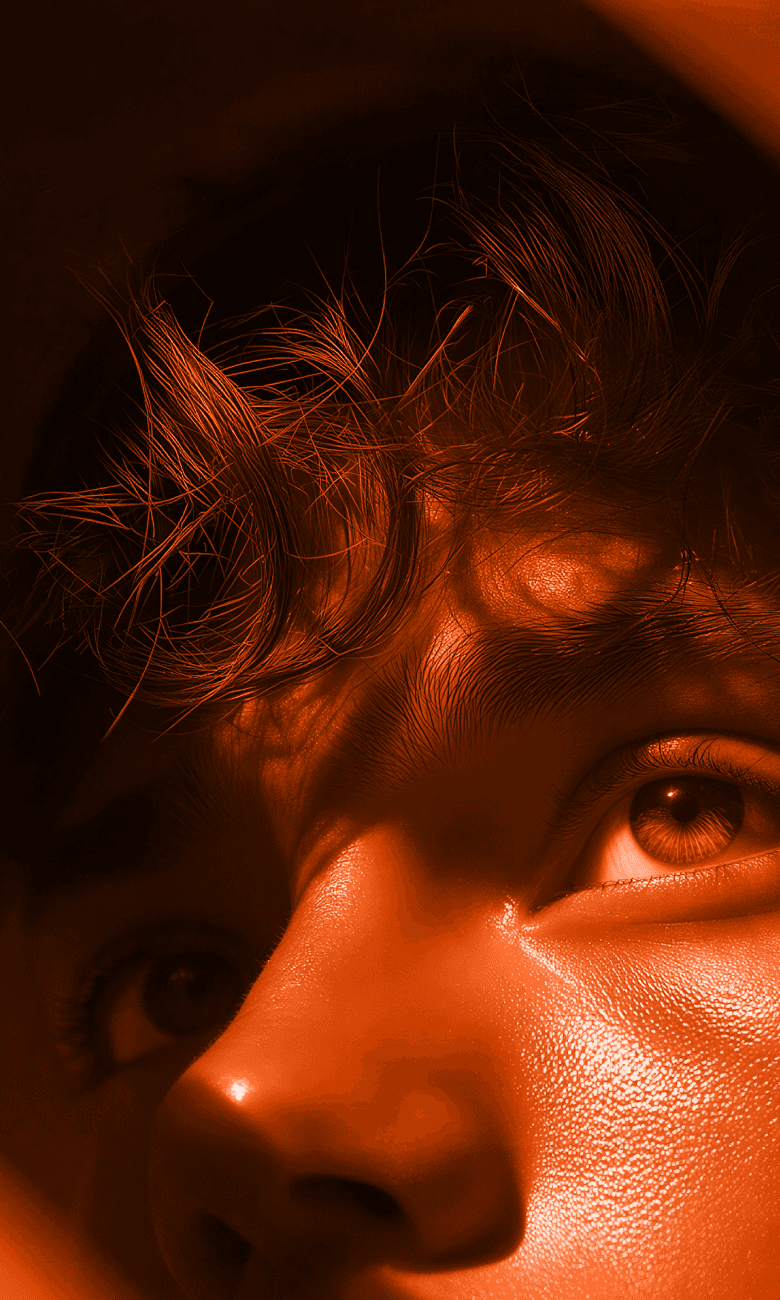Close-up of a man's eye lit in warm orange light.